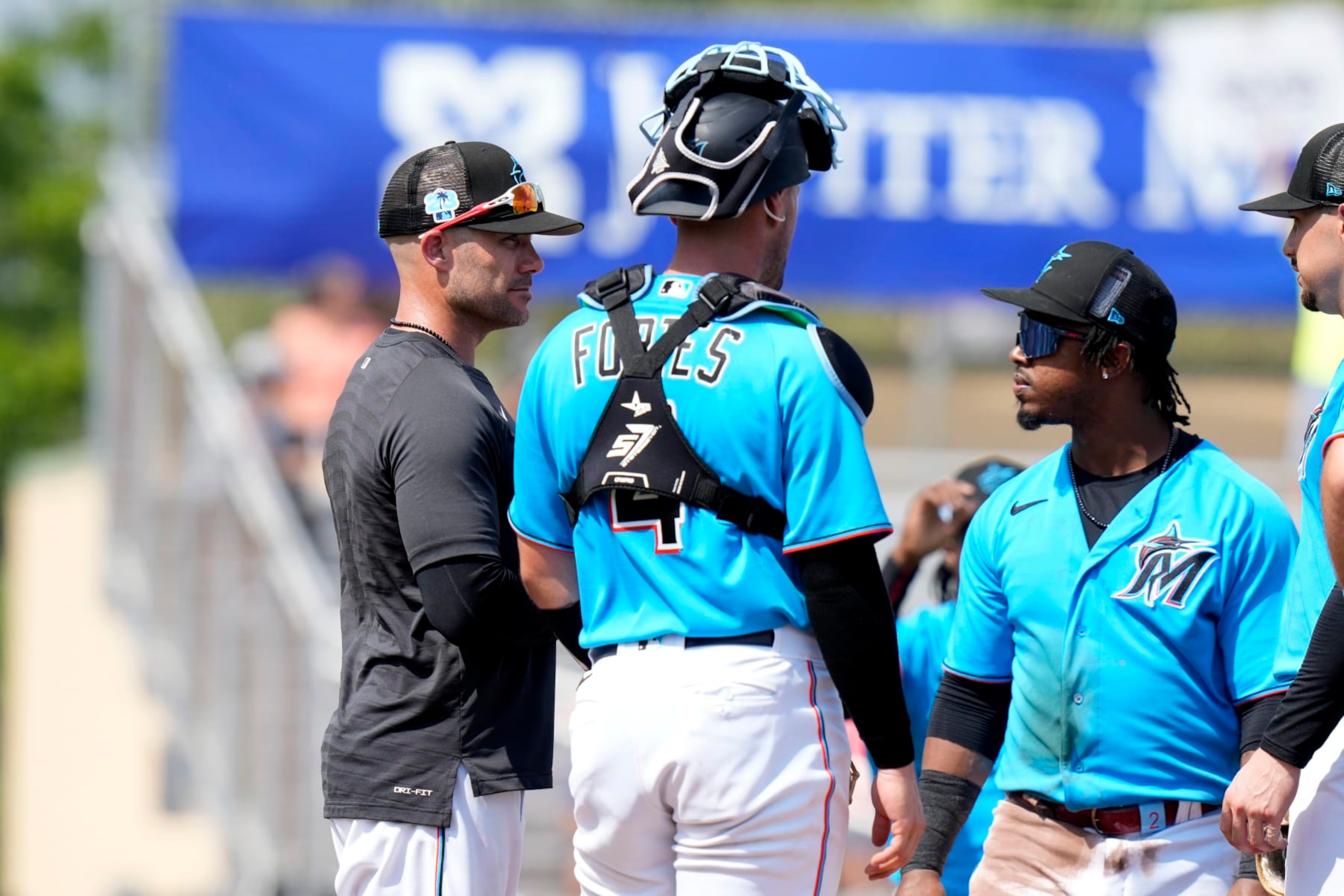 Miami Marlins manager Skip Schumaker, left, stands on the mound with catcher Nick Fortes (4) and relief pitcher George Soriano, right, during the third inning of a spring training baseball game against the New York Mets, Saturday, March 4, 2023, in Jupiter, Fla. (AP Photo/Lynne Sladky)