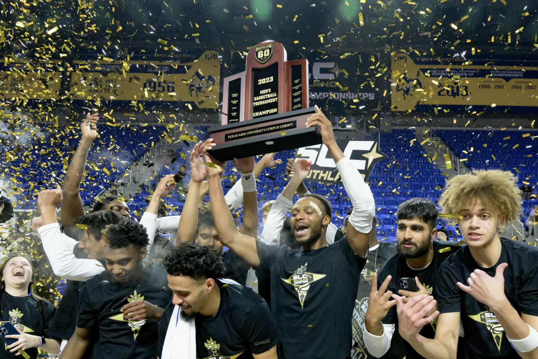 Texas A&M Corpus Christi forward Isaac Mushila hoists the championship trophy after the team defeated Northwestern State during an NCAA college basketball game in the finals of the Southland Conference men's tournament in Lake Charles, La., Wednesday, March 8, 2023. (AP Photo/Matthew Hinton)
