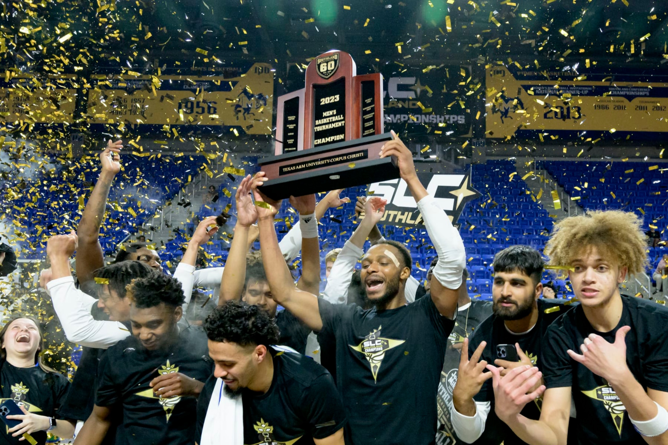 Texas A&M Corpus Christi forward Isaac Mushila hoists the championship trophy after the team defeated Northwestern State during an NCAA college basketball game in the finals of the Southland Conference men's tournament in Lake Charles, La., Wednesday, March 8, 2023. (AP Photo/Matthew Hinton)