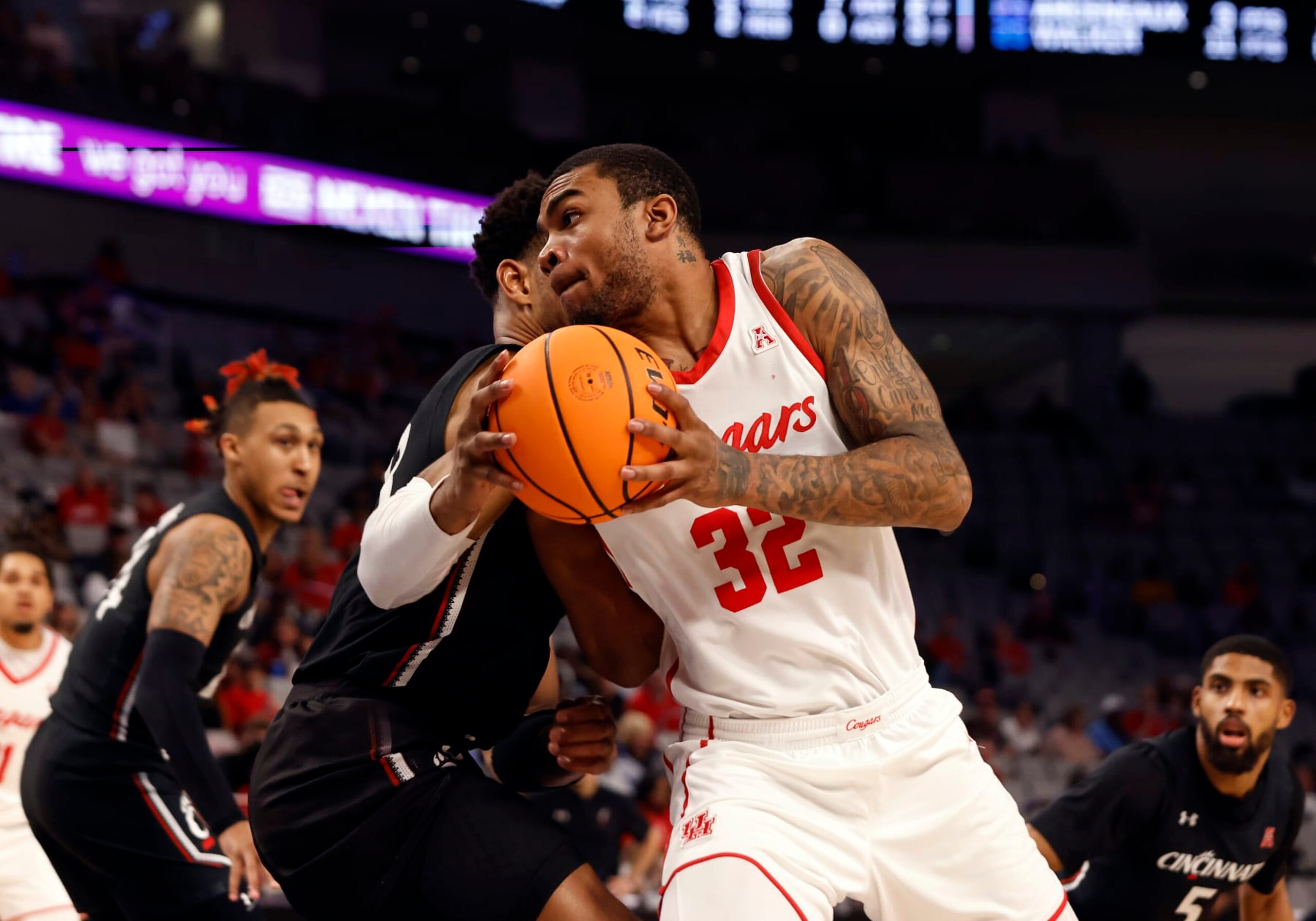 FORT WORTH, TX - MARCH 11: Houston Cougars forward Reggie Chaney (32) dribbles past Cincinnati Bearcats guard Mika Adams  Woods (3) during the semifinal game of the American Athletic Conference Tournament at the Dickies Arena in Forth Worth, TX on March 11, 2023. (Photo by Adam Davis/Icon Sportswire via Getty Images)
