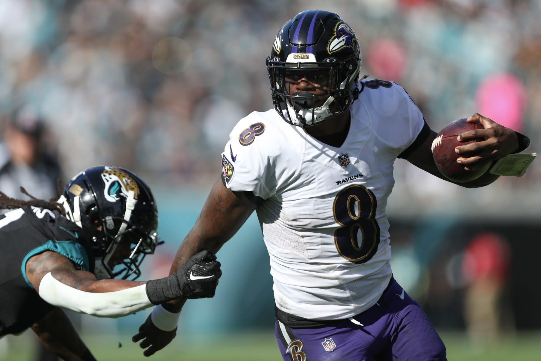 JACKSONVILLE, FLORIDA - NOVEMBER 27: Lamar Jackson #8 of the Baltimore Ravens carries the ball defended by Rayshawn Jenkins #2 of the Jacksonville Jaguars during the first half at TIAA Bank Field on November 27, 2022 in Jacksonville, Florida. (Photo by Courtney Culbreath/Getty Images)