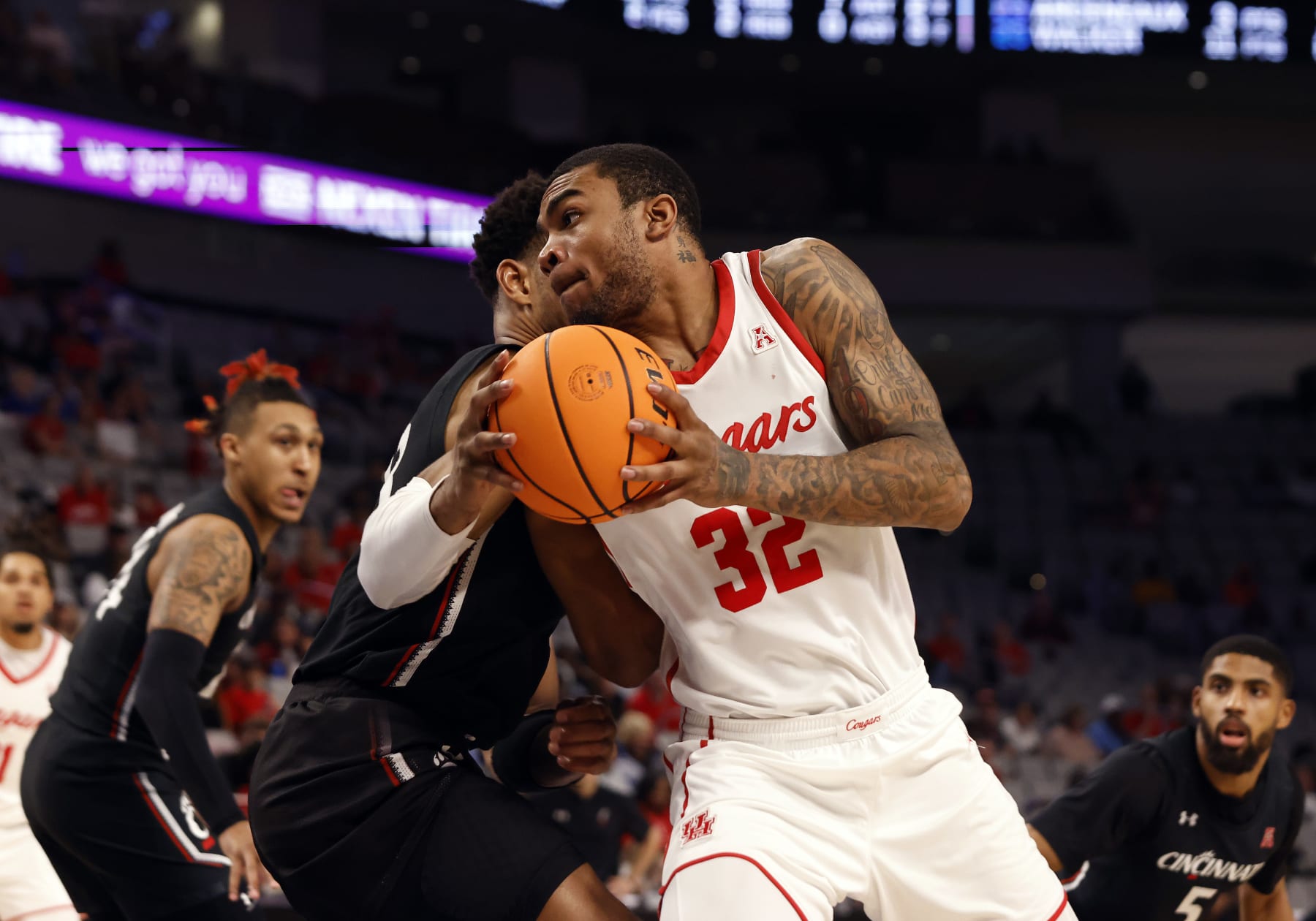 FORT WORTH, TX - MARCH 11: Houston Cougars forward Reggie Chaney (32) dribbles past Cincinnati Bearcats guard Mika Adams  Woods (3) during the semifinal game of the American Athletic Conference Tournament at the Dickies Arena in Forth Worth, TX on March 11, 2023. (Photo by Adam Davis/Icon Sportswire via Getty Images)