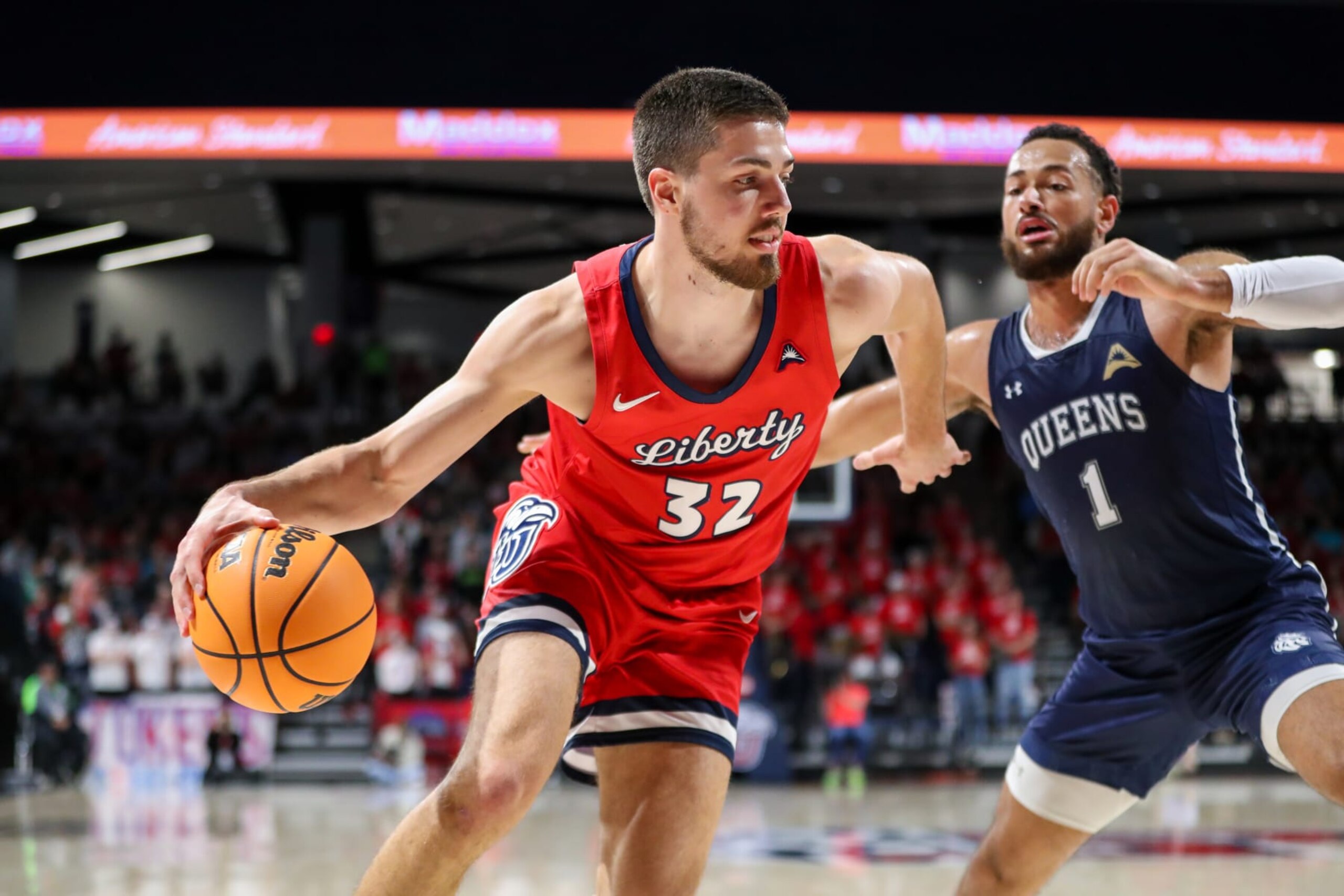 LYNCHBURG, VA - FEBRUARY 24: Mike Fowler (1) of the Queens Royals defends Blake Preston (32) of the Liberty Flames as he drives to the basket during a basketball game on February 24, 2023 at Liberty Arena in Lynchburg, VA. (Photo by David Jensen/Icon Sportswire via Getty Images)