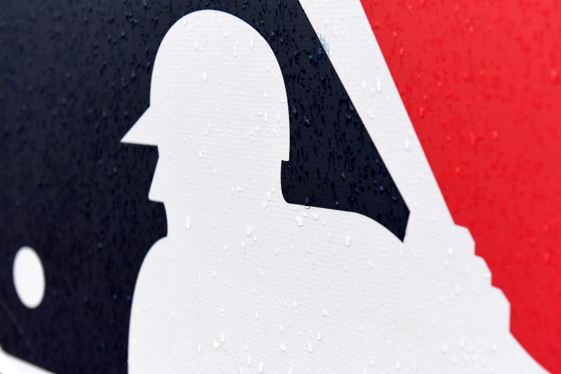 CLEVELAND, OH - AUGUST 21: A closeup view of the Major League Baseball logo as rain falls prior to a game between the Chicago White Sox and the Cleveland Guardians at Progressive Field on August 21, 2022 in Cleveland, Ohio. The game was postponed due to unsafe field conditions. (Photo by Nick Cammett/Diamond Images via Getty Images)