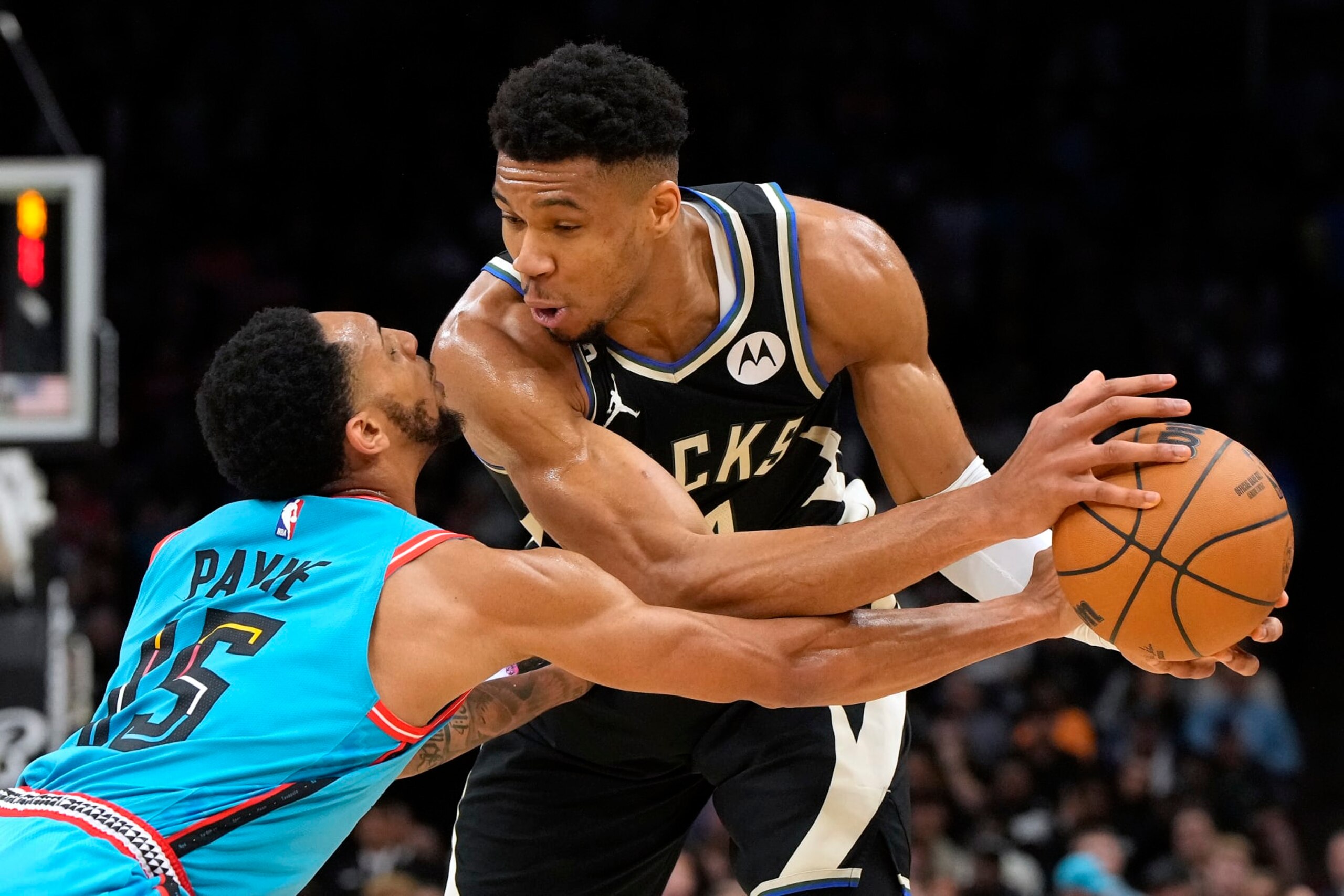 Phoenix Suns guard Cameron Payne (15) reaches for the ball held by Milwaukee Bucks forward Giannis Antetokounmpo (34) during the first half of an NBA basketball game Tuesday, March 14, 2023, in Phoenix. (AP Photo/Rick Scuteri)