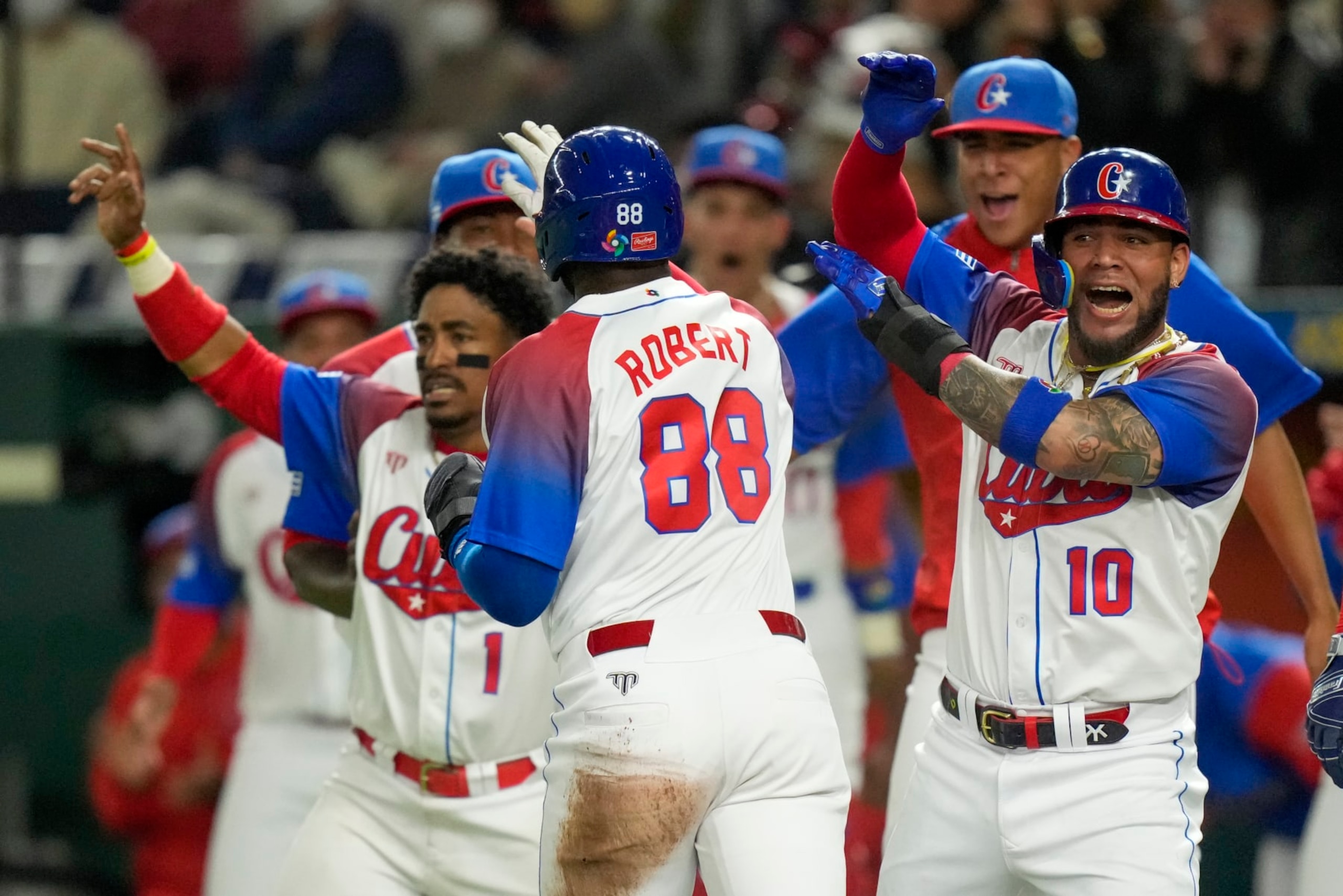 Yoan Moncada, right, of Cuba congratulates teammate Luis Robert Jr. as he runs home during the World Baseball Classic quarterfinal game between Cuba and Australia at the Tokyo Dome Tokyo, Wednesday, March 15, 2023. (AP Photo/Eugene Hoshiko)
