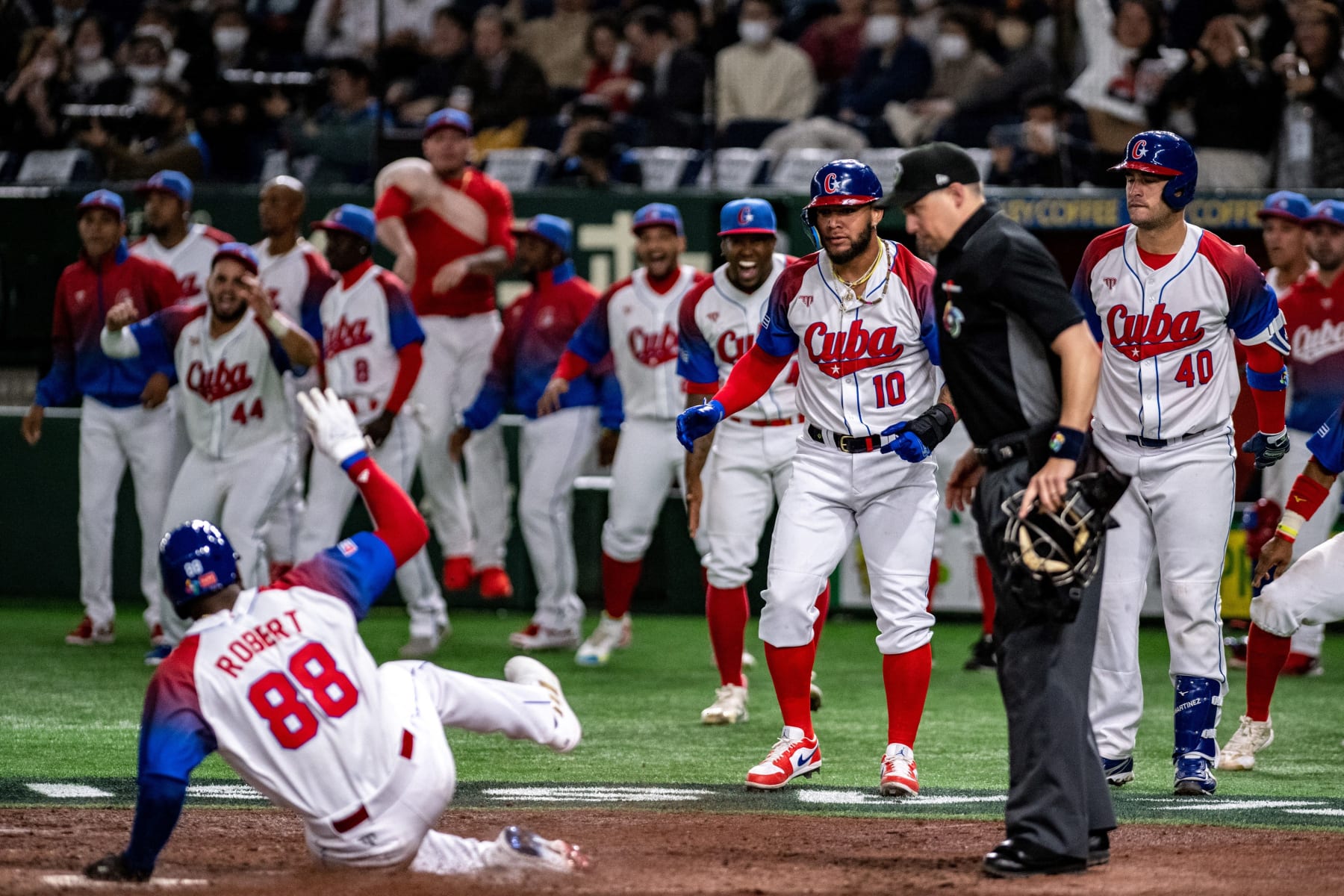 Members of Team Cuba reacts as Cuba's Luis Robert Jr. sliding to home plate during the World Baseball Classic (WBC) quarter-final game between Cuba and Australia at the Tokyo Dome in Tokyo on March 15, 2023. (Photo by Philip FONG / AFP) (Photo by PHILIP FONG/AFP via Getty Images)