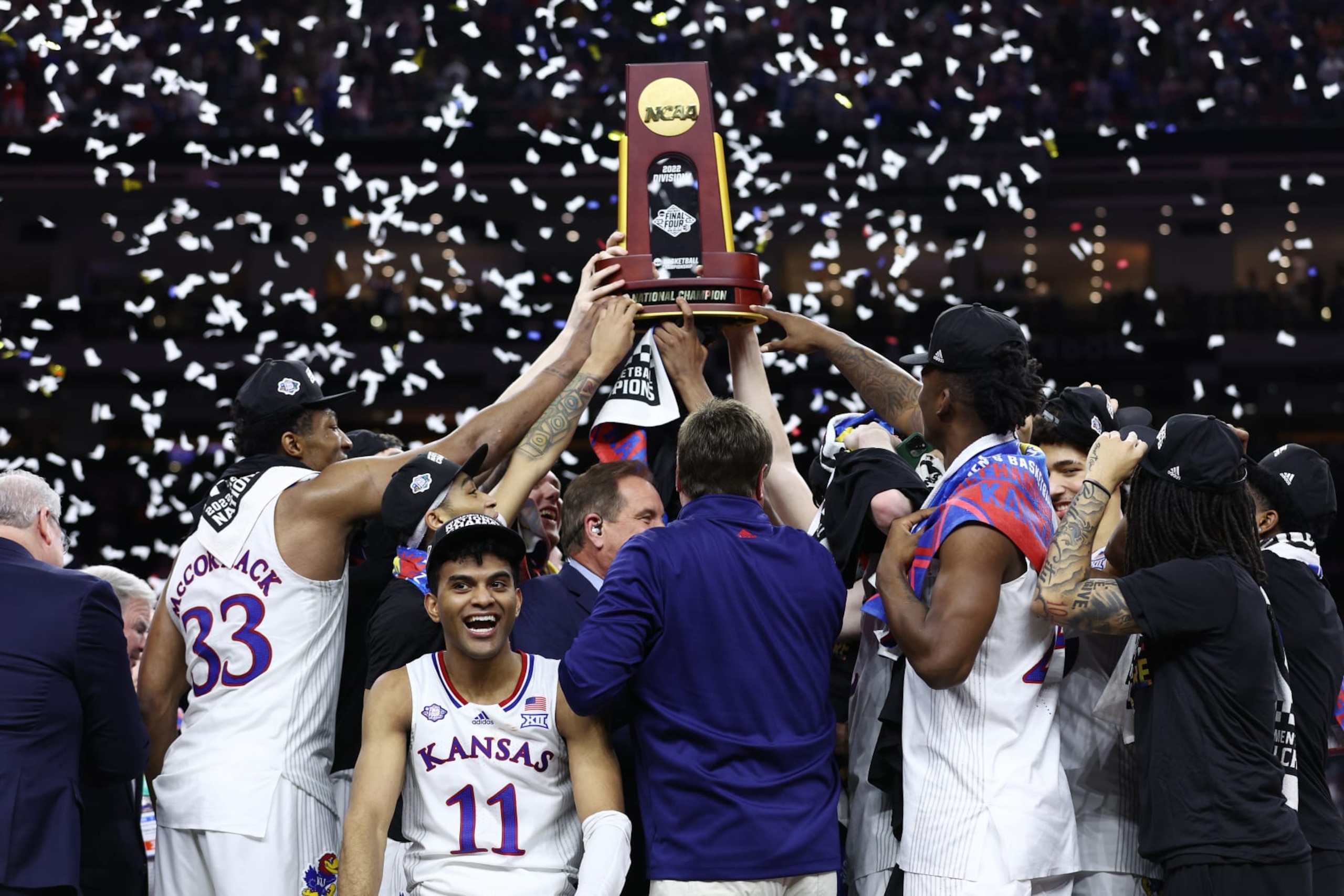 NEW ORLEANS, LOUISIANA - APRIL 04: Remy Martin #11 of the Kansas Jayhawks reacts as Kansas Jayhawks players and coaches hold up the trophy after defeating the North Carolina Tar Heels 72-69 during the 2022 NCAA Men's Basketball Tournament National Championship at Caesars Superdome on April 04, 2022 in New Orleans, Louisiana. (Photo by Tom Pennington/Getty Images)