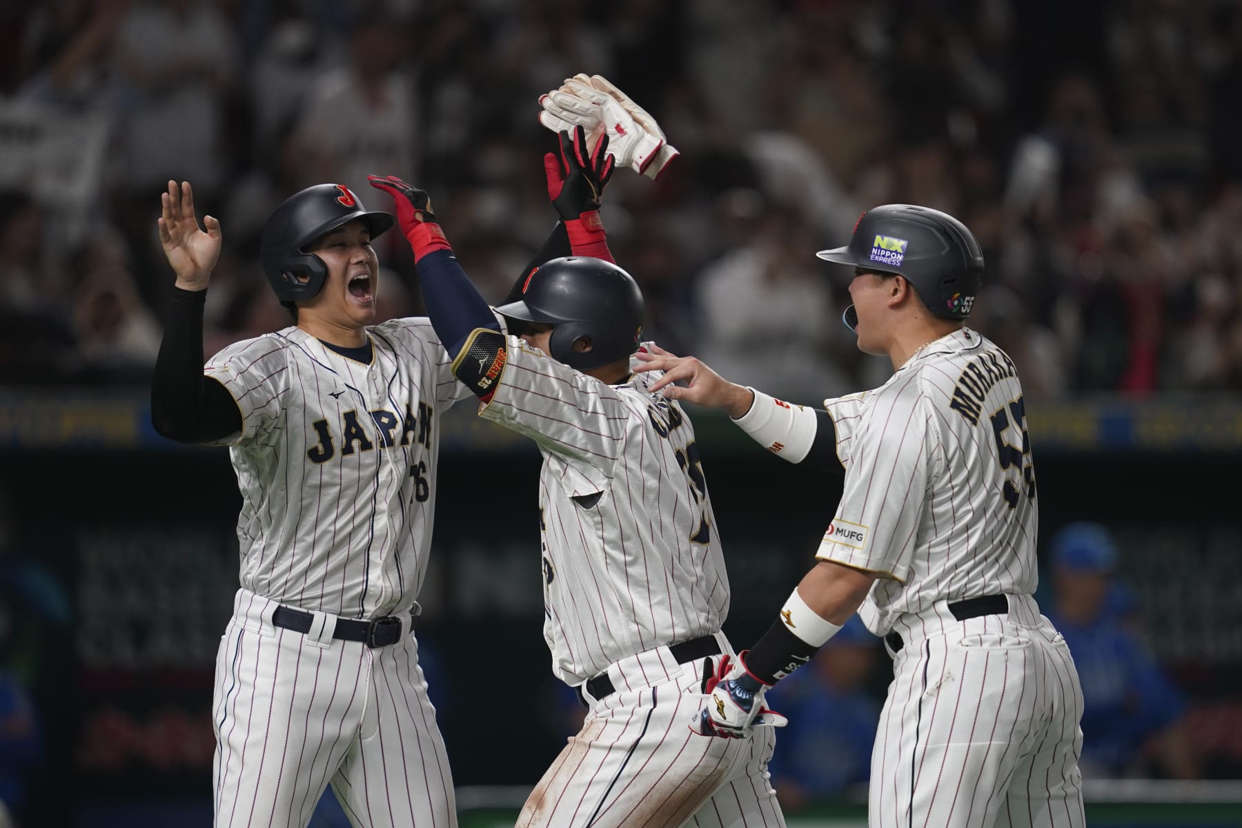 Kazuma Okamoto of Japan, center celebrates with Shohei Ohtani of Japan, left, and Munetaka Murakami of Japan after hitting a three-run home run during the third inning of the quarterfinal game between Italy and Japan at the World Baseball Classic (WBC) at Tokyo Dome in Tokyo, Japan, Thursday, March 16, 2023. (AP Photo/Toru Hanai)