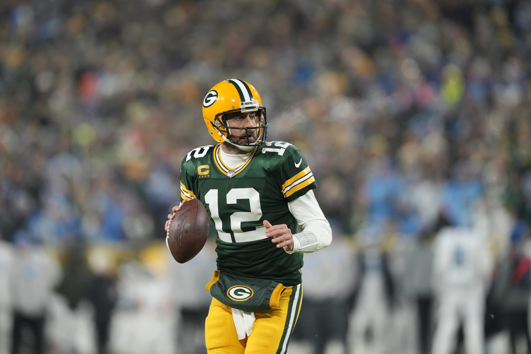 GREEN BAY, WISCONSIN - JANUARY 08: Aaron Rodgers #12 of the Green Bay Packers scrambles with the ball against the Detroit Lions in the first half at Lambeau Field on January 08, 2023 in Green Bay, Wisconsin. (Photo by Patrick McDermott/Getty Images)