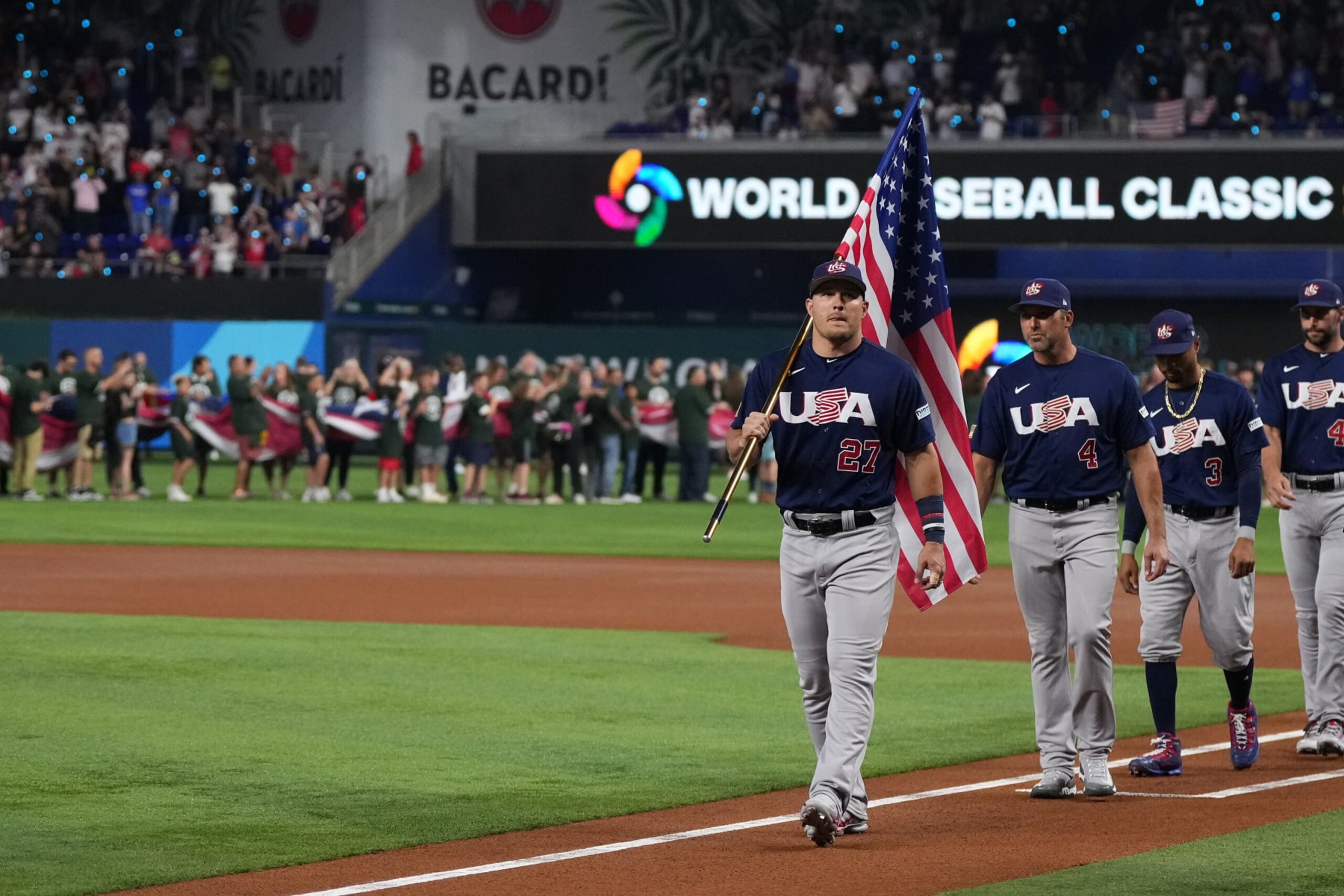 MIAMI, FL - MARCH 21: Mike Trout #27 of the United States leads his teammates while carrying the American flag prior to the game against Japan at loanDepot park on March 21, 2023 in Miami, Florida. (Photo by Jasen Vinlove/Miami Marlins/Getty Images)