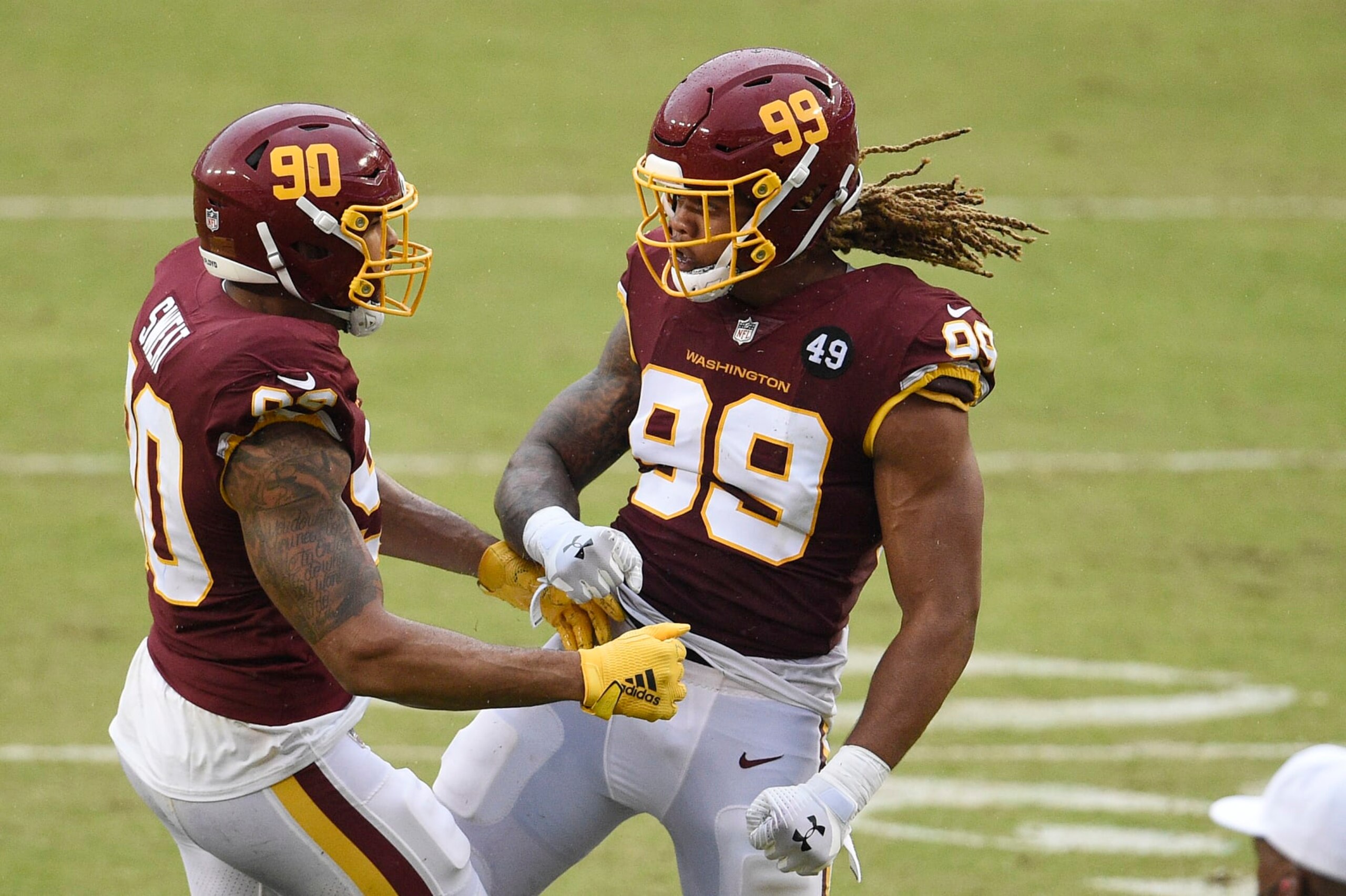 LANDOVER, MARYLAND - OCTOBER 11: Montez Sweat #90 of the Washington Football Team celebrates with teammate Chase Young #99 after a play in the second half against the Los Angeles Rams at FedExField on October 11, 2020 in Landover, Maryland. (Photo by Patrick McDermott/Getty Images)