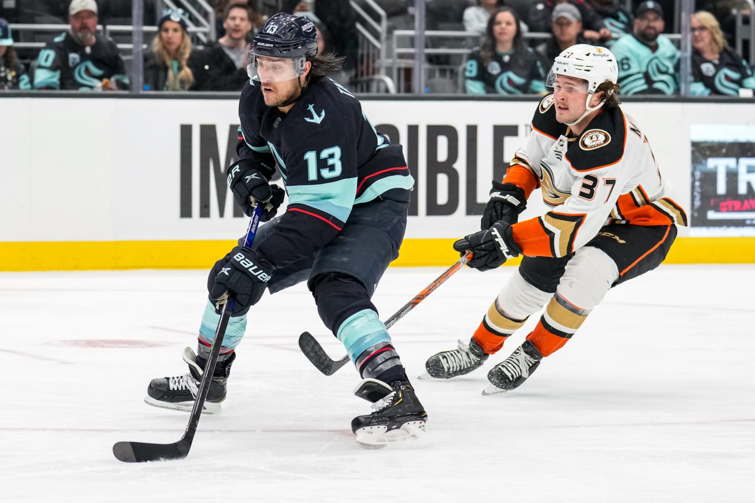 SEATTLE, WASHINGTON - MARCH 30:Brandon Tanev #13 of the Seattle Kraken skates with the puck as Mason McTavish #37 of the Anaheim Ducks pursues closely behind during the second period of a game at Climate Pledge Arena on March 30, 2023 in Seattle, Washington. (Photo by Christopher Mast/NHLI via Getty Images)