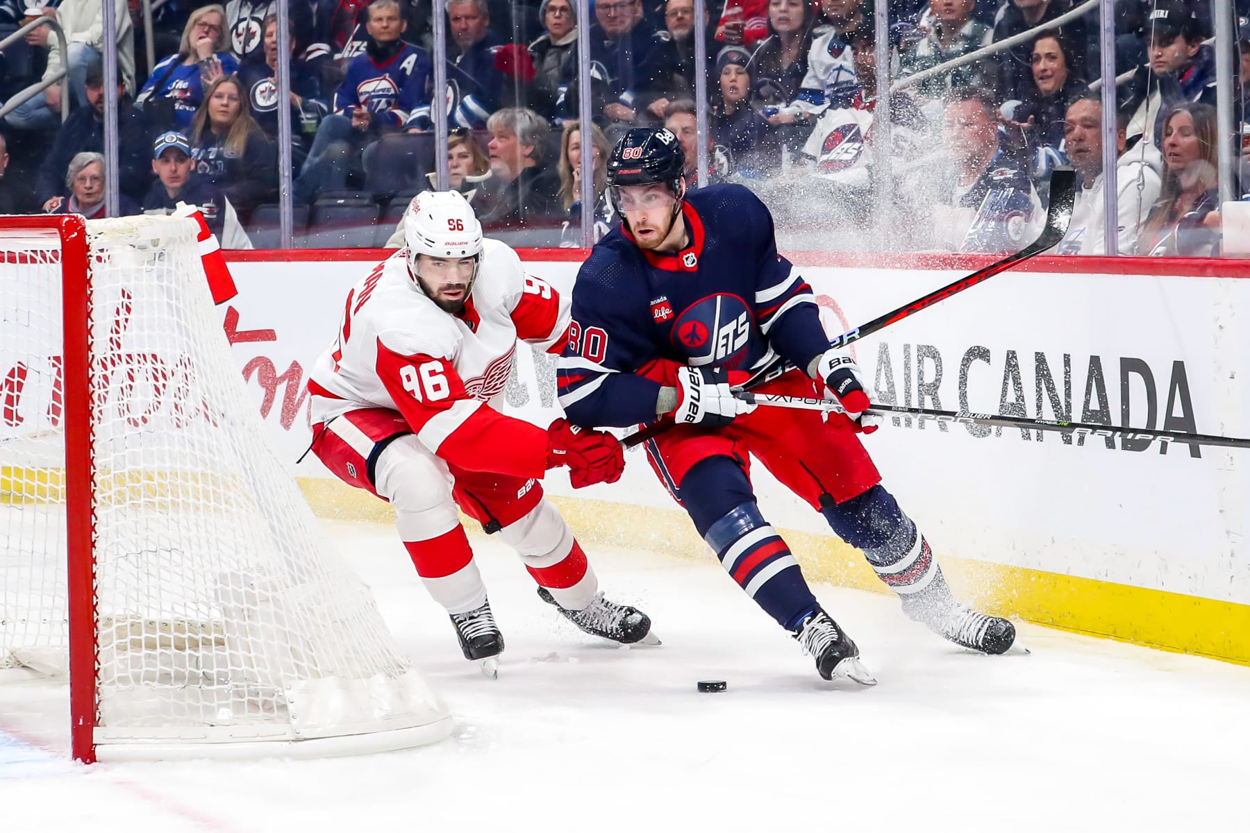 WINNIPEG, CANADA - MARCH 31: Jake Walman #96 of the Detroit Red Wings and Pierre-Luc Dubois #80 of the Winnipeg Jets battle for the puck behind the net during first period action at the Canada Life Centre on March 31, 2023 in Winnipeg, Manitoba, Canada. (Photo by Darcy Finley/NHLI via Getty Images)