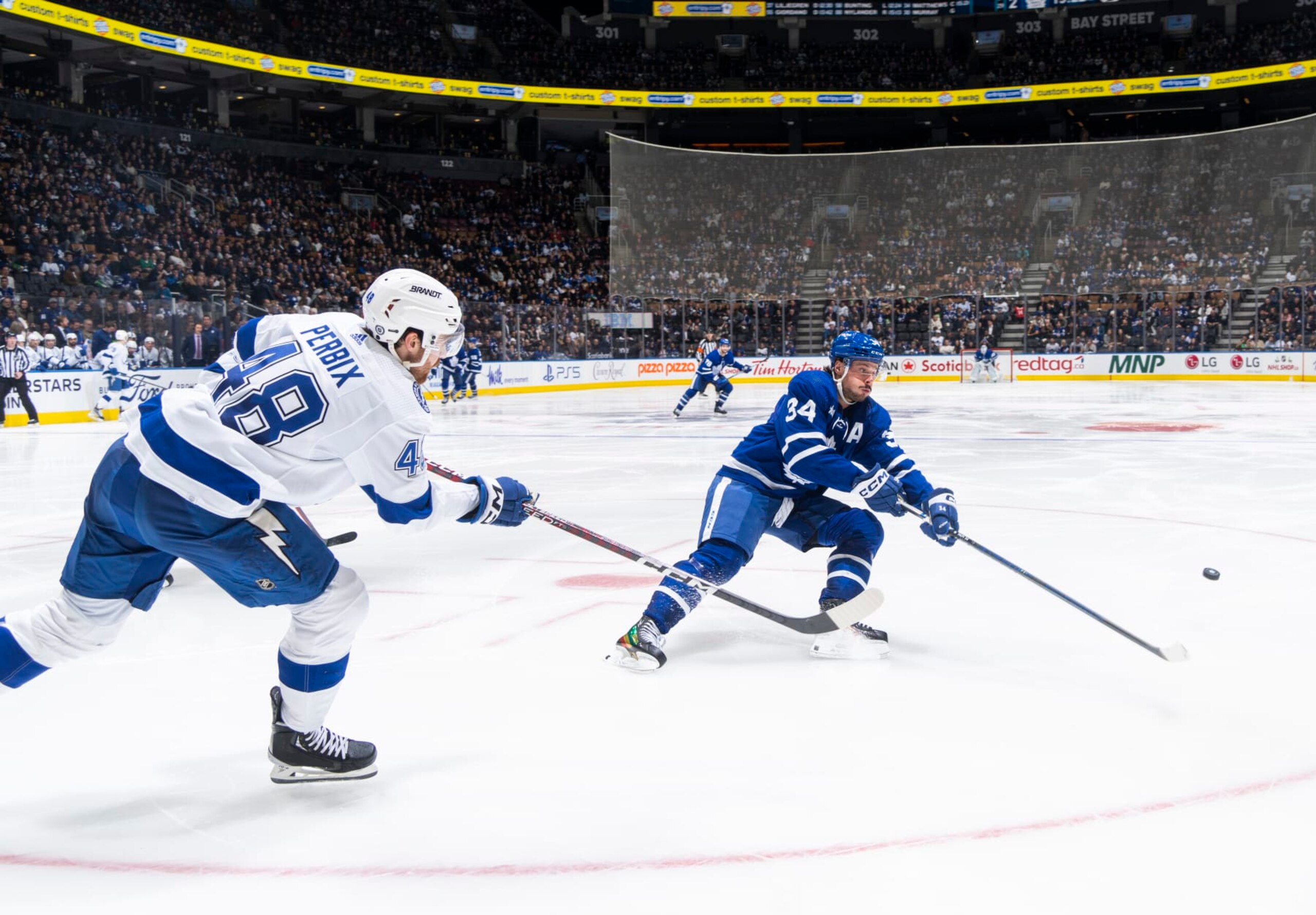 TORONTO, ON - DECEMBER 20: Nick Perbix #48 of the Tampa Bay Lightning passes the puck against Auston Matthews #34 of the Toronto Maple Leafs during the third period at the Scotiabank Arena on December 20, 2022 in Toronto, Ontario, Canada. (Photo by Mark Blinch/NHLI via Getty Images)