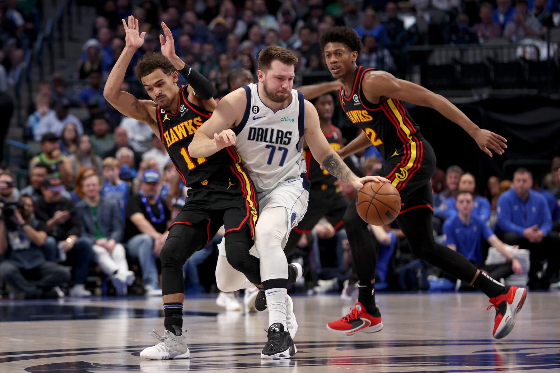 DALLAS, TEXAS - JANUARY 18: Luka Doncic #77 of the Dallas Mavericks dribbles the ball against Trae Young #11 of the Atlanta Hawks and De'Andre Hunter #12 of the Atlanta Hawks in the first quart at American Airlines Center on January 18, 2023 in Dallas, Texas. NOTE TO USER: User expressly acknowledges and agrees that, by downloading and or using this photograph, User is consenting to the terms and conditions of the Getty Images License Agreement. (Photo by Tom Pennington/Getty Images)