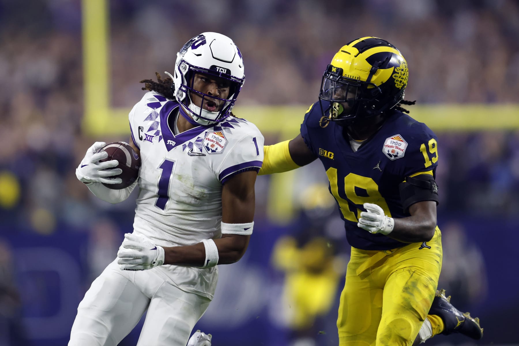 GLENDALE, ARIZONA - DECEMBER 31: Wide receiver Quentin Johnston #1 of the TCU Horned Frogs is tackled by defensive back Rod Moore #19 of the Michigan Wolverines during the second half of the Vrbo Fiesta Bowl at State Farm Stadium on December 31, 2022 in Glendale, Arizona. The Horned Frogs defeated the Wolverines 51-45. (Photo by Chris Coduto/Getty Images)