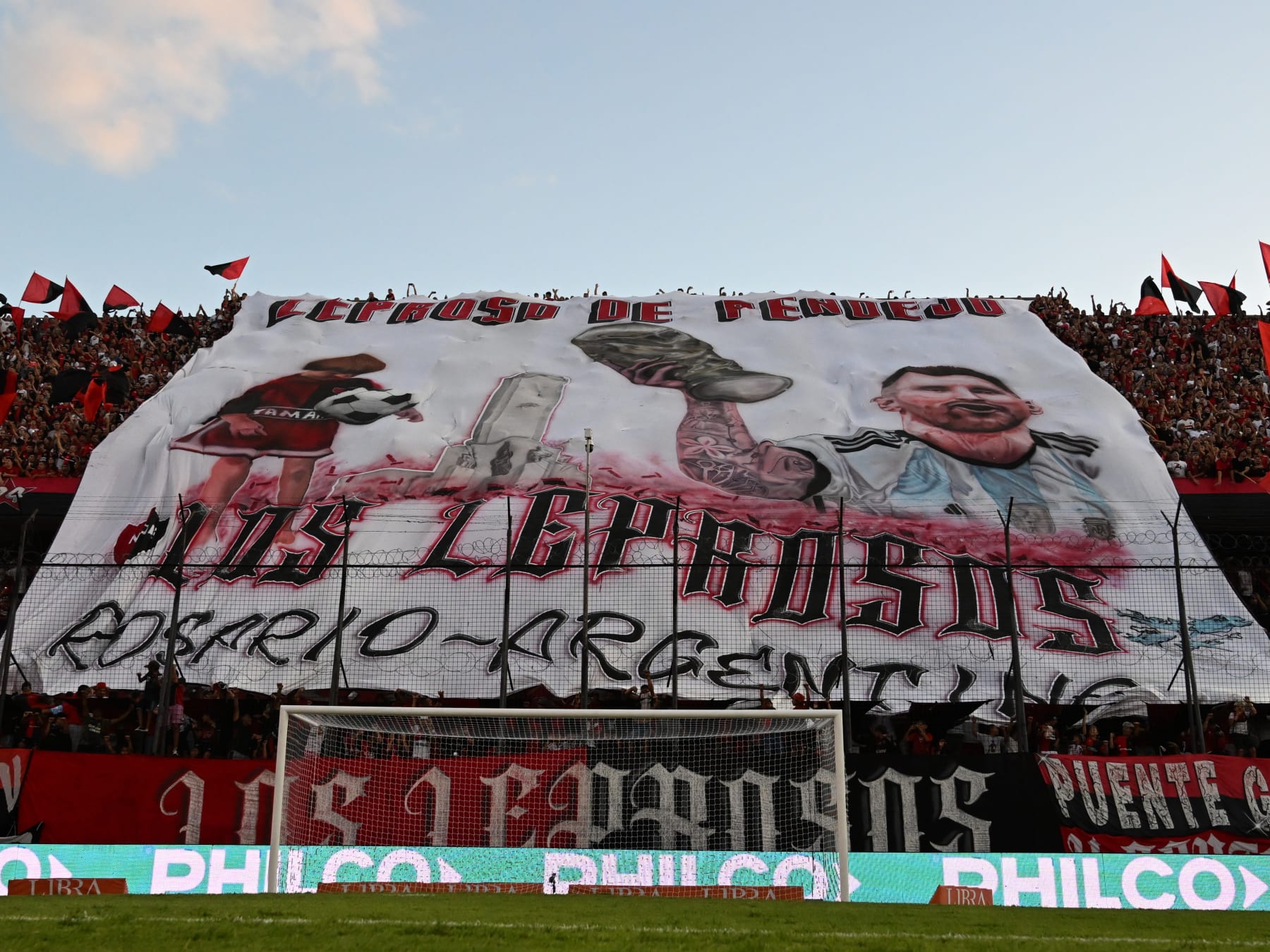 ROSARIO, ARGENTINA - FEBRUARY 03: Fans of Newell´s Old Boys display a flag with the image of Lionel Messi holding the World Cup Trophy previous a match between Newell's Old Boys and Velez as part of Liga Profesional 2023 at Marcelo Bielsa Stadium on February 3, 2023 in Rosario, Argentina. (Photo by Luciano Bisbal/Getty Images)