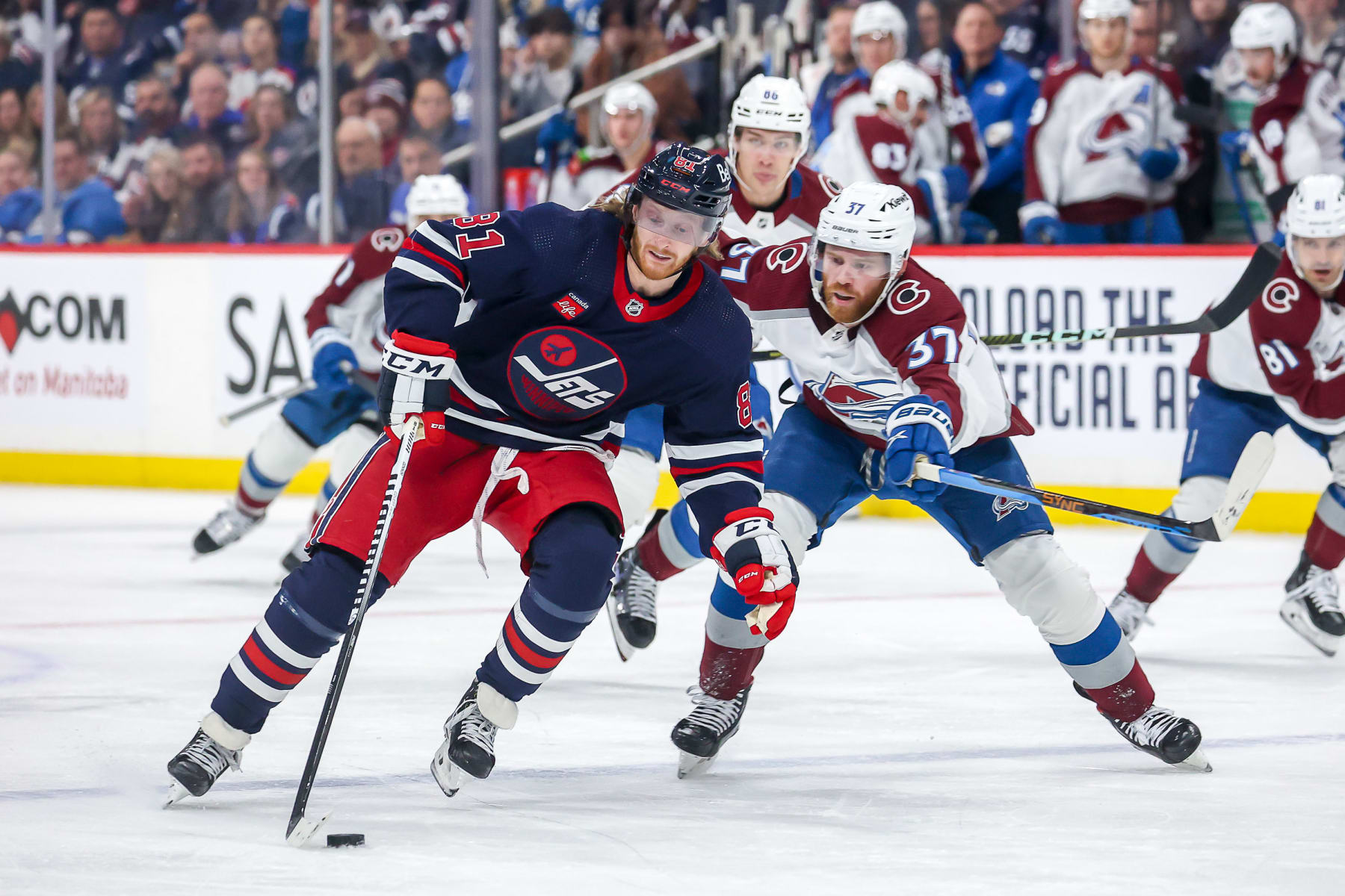 Winnipeg Jets winger Kyle Connor wards off Colorado Avalanche center J.T. Compher.