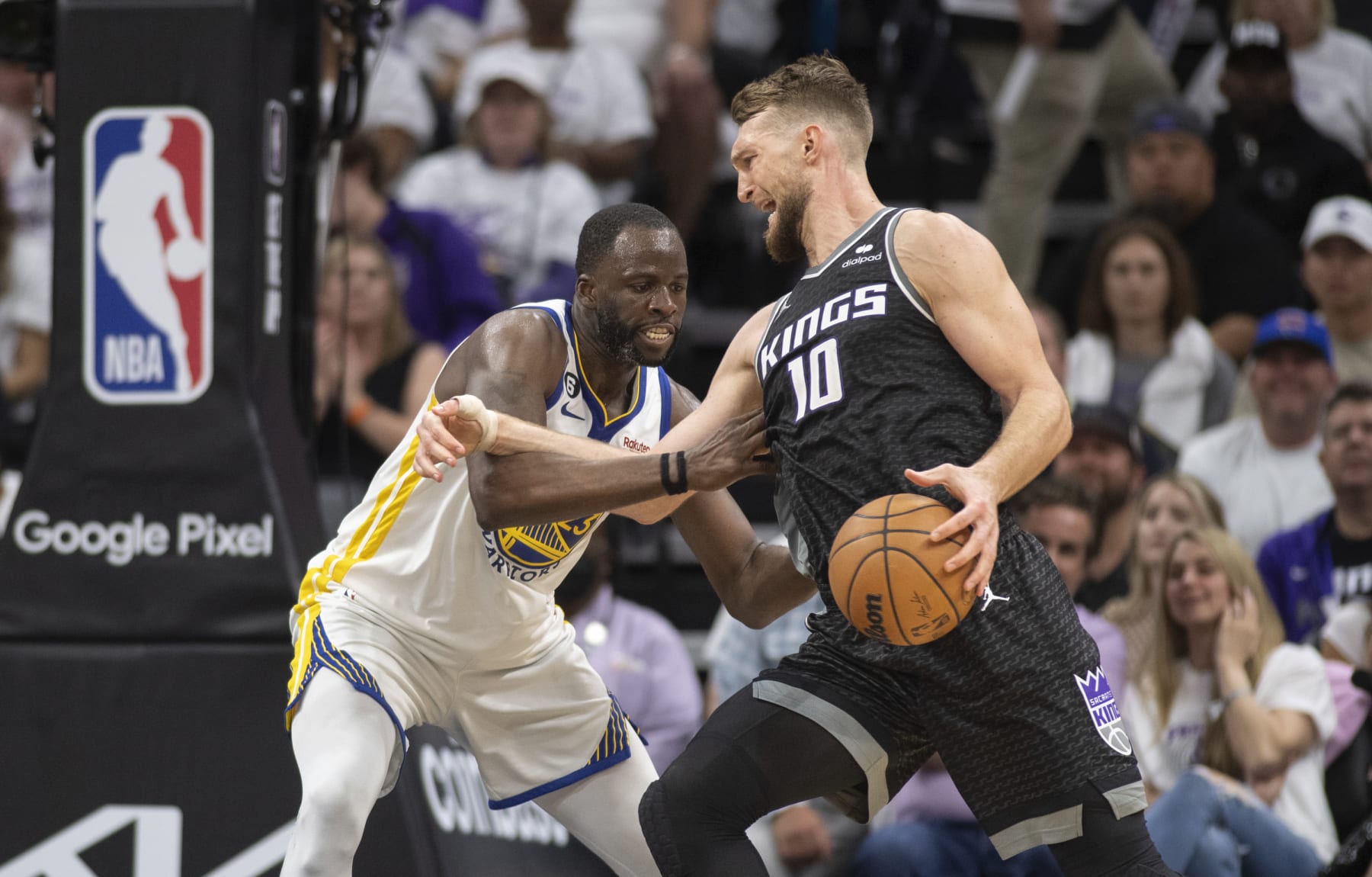 Golden State Warriors forward Draymond Green (23) defends Sacramento Kings forward Domantas Sabonis (10) in the fourth quarter during Game 1 in the first round of the NBA basketball playoffs in Sacramento, Calif., Saturday, April 15, 2023. The Kings won 126-123. (AP Photo/José Luis Villegas)