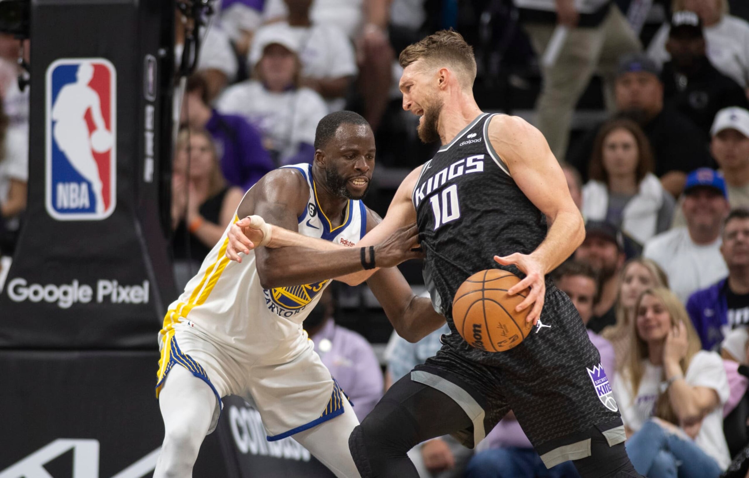 Golden State Warriors forward Draymond Green (23) defends Sacramento Kings forward Domantas Sabonis (10) in the fourth quarter during Game 1 in the first round of the NBA basketball playoffs in Sacramento, Calif., Saturday, April 15, 2023. The Kings won 126-123. (AP Photo/José Luis Villegas)