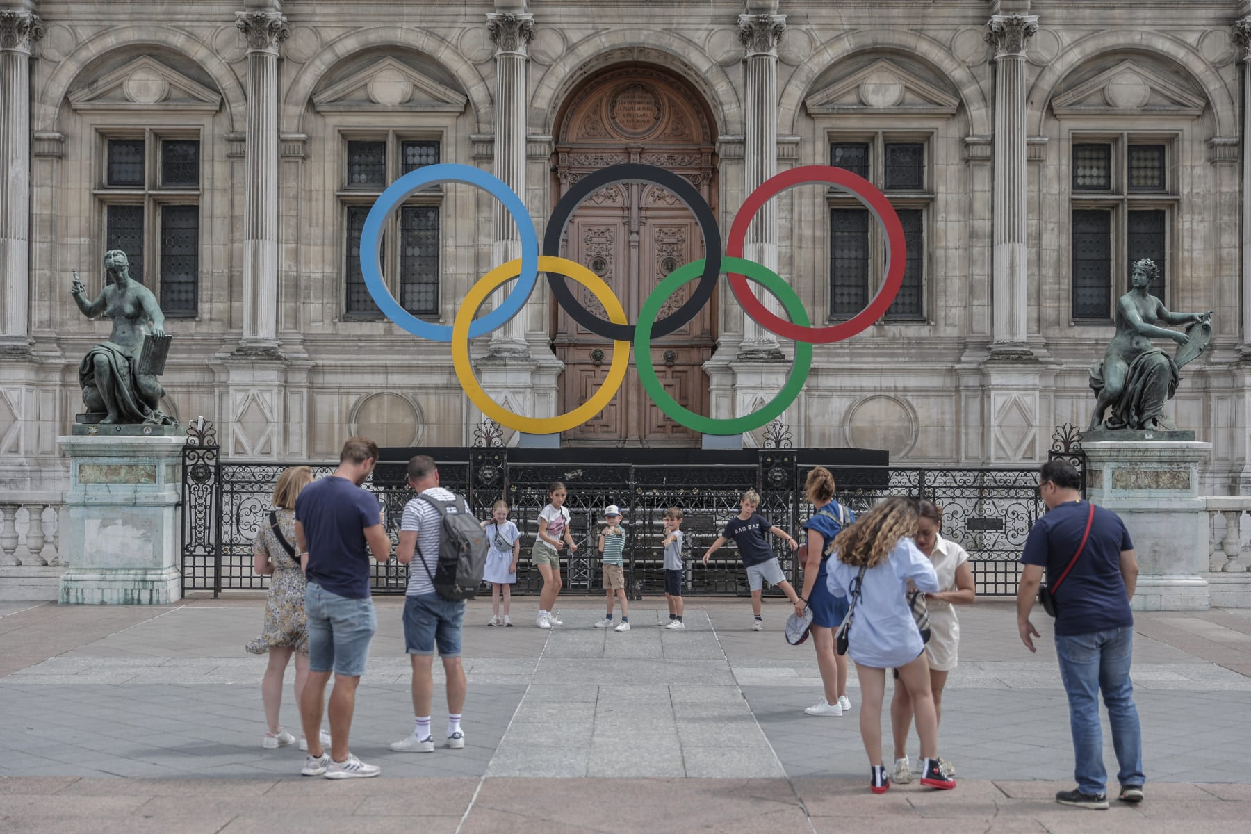 People gather at the Olympic rings at the City Hall in Paris, Monday, July 25, 2022. Tomorrow is marking two years until the Olympics are due to begin in the French capital. (AP Photo/Lewis Joly)