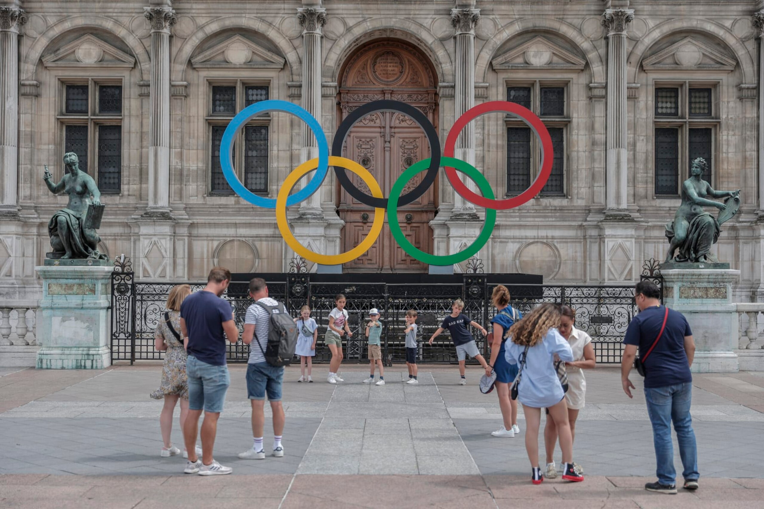 People gather at the Olympic rings at the City Hall in Paris, Monday, July 25, 2022. Tomorrow is marking two years until the Olympics are due to begin in the French capital. (AP Photo/Lewis Joly)