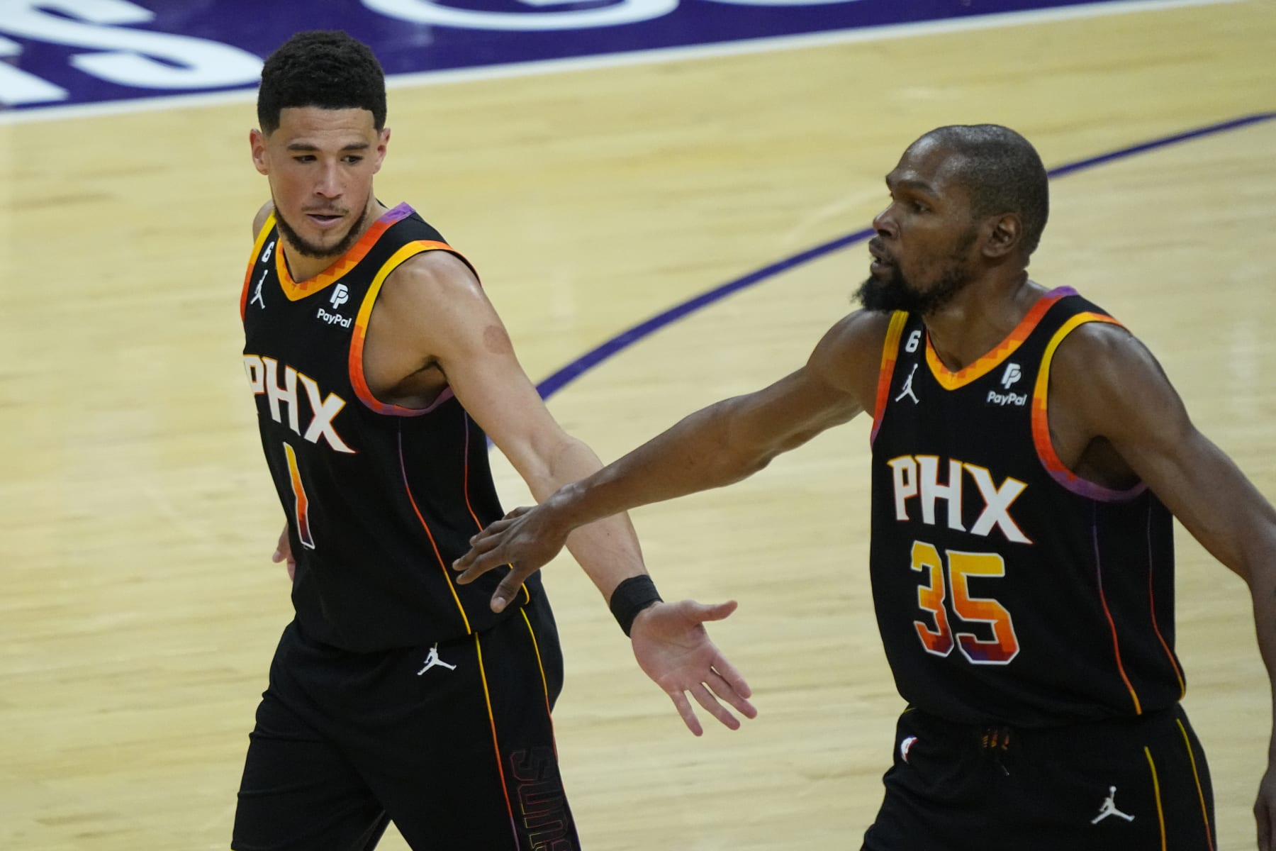 Phoenix Suns guard Devin Booker (1) and forward Kevin Durant (35) celebrate a basket against the Los Angeles Clippers during the second half of Game 1 of a first-round NBA basketball playoff series, Sunday, April 16, 2023, in Phoenix. (AP Photo/Matt York)