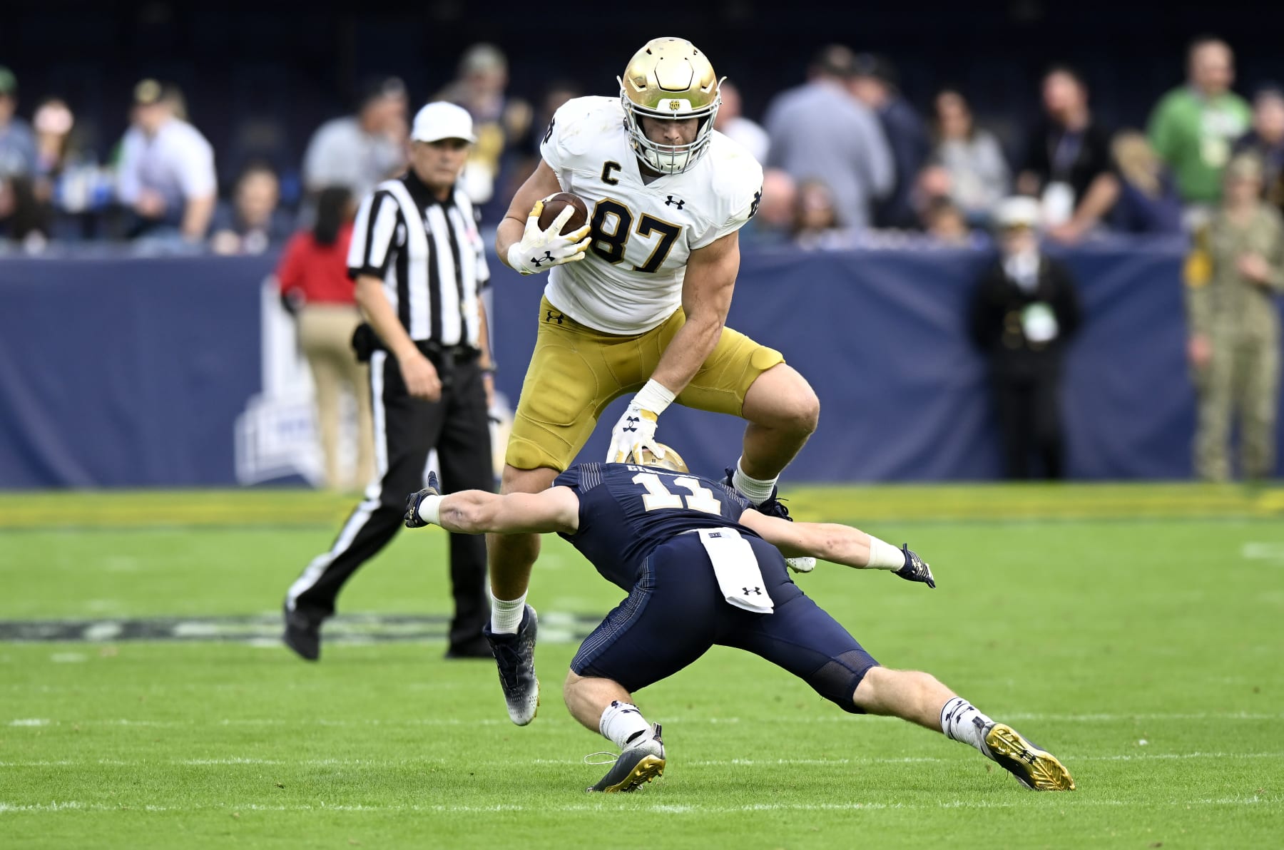 BALTIMORE, MARYLAND - NOVEMBER 12: Michael Mayer #87 of the Notre Dame Fighting Irish jumps over Eavan Gibbons #11 of the Navy Midshipmen in the fourth quarter at M&T Bank Stadium on November 12, 2022 in Baltimore, Maryland. (Photo by Greg Fiume/Getty Images)