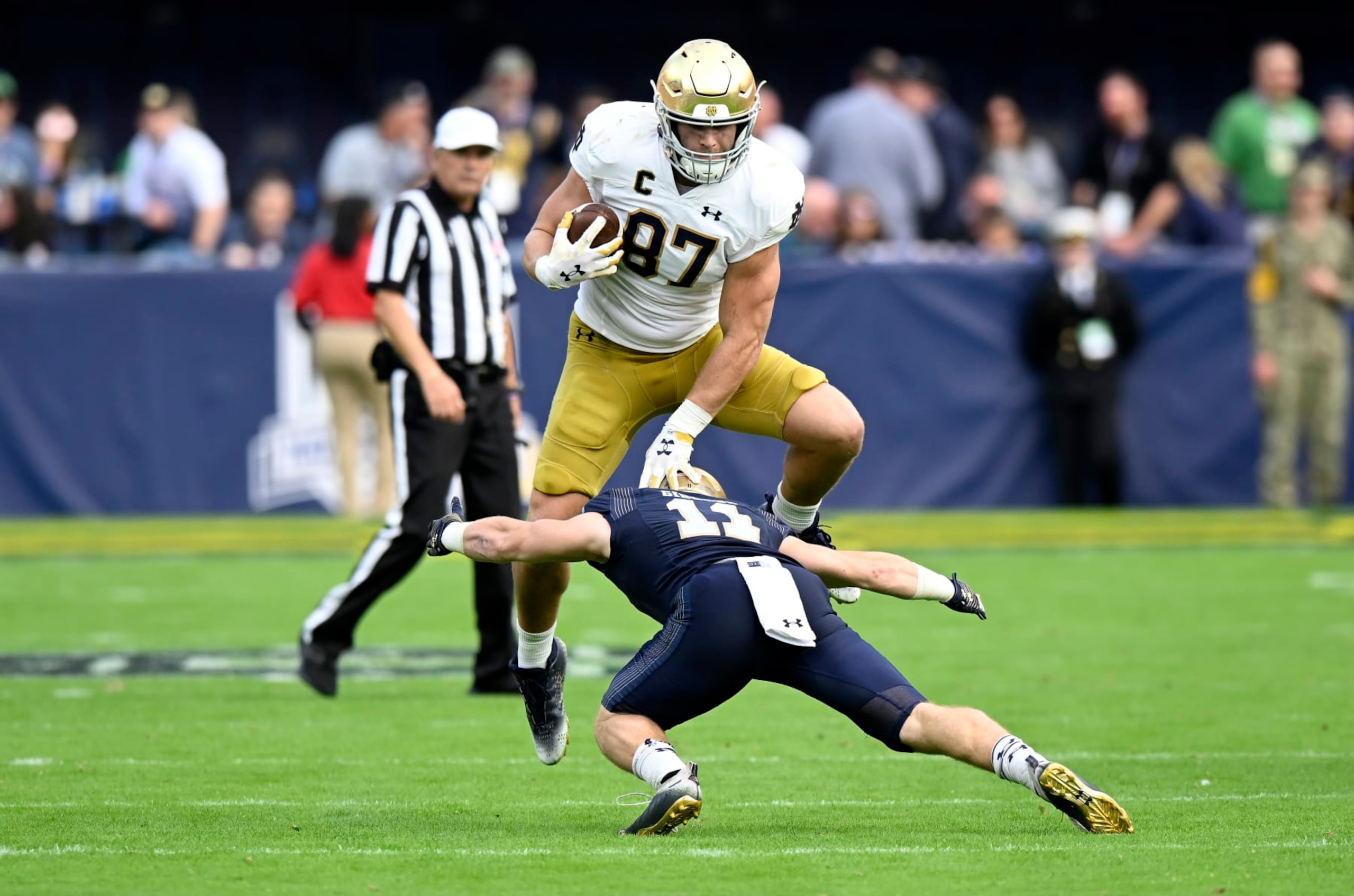 BALTIMORE, MARYLAND - NOVEMBER 12: Michael Mayer #87 of the Notre Dame Fighting Irish jumps over Eavan Gibbons #11 of the Navy Midshipmen in the fourth quarter at M&T Bank Stadium on November 12, 2022 in Baltimore, Maryland. (Photo by Greg Fiume/Getty Images)