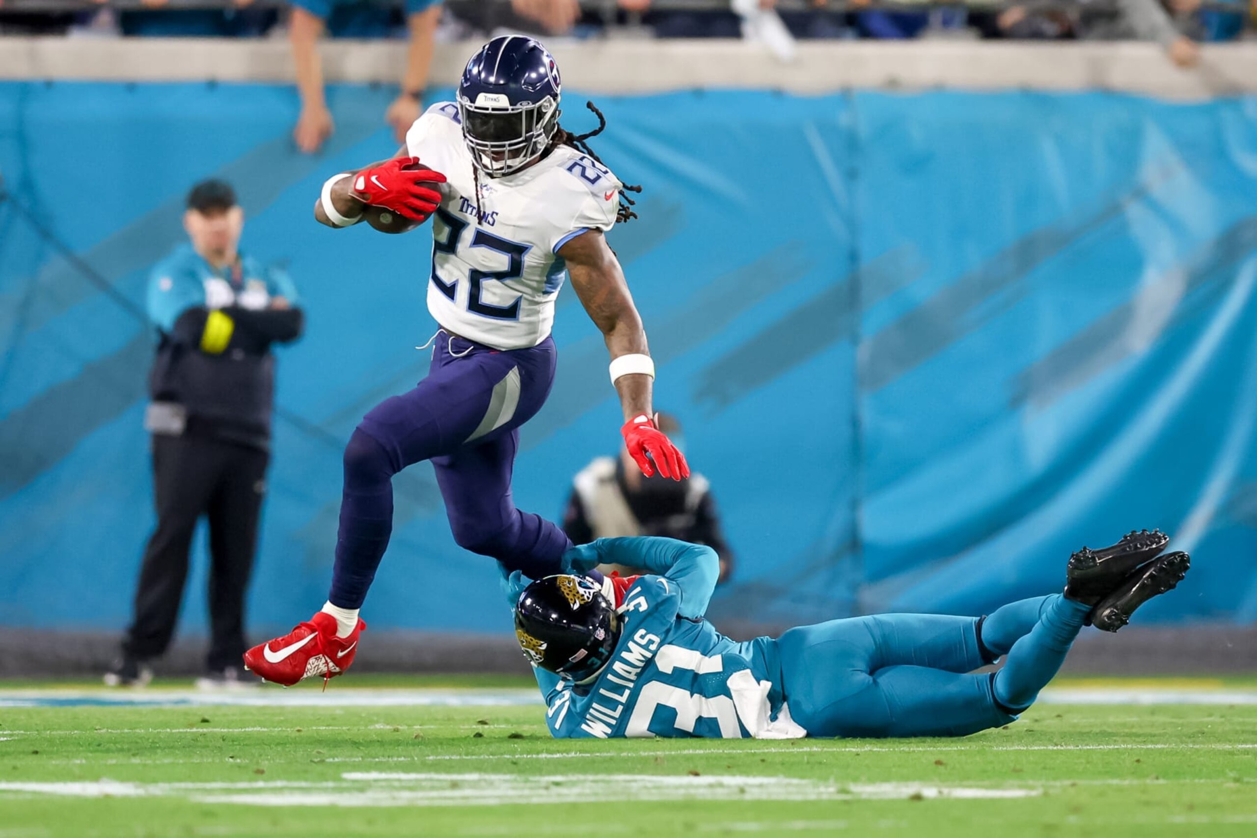 JACKSONVILLE, FLORIDA - JANUARY 8: Derrick Henry #22 of the Tennessee Titans breaks the tackle of Darious Williams #31 of the Jacksonville Jaguars at TIAA Bank Field on January 8, 2023 in Jacksonville, Florida. (Photo by Mike Carlson/Getty Images)