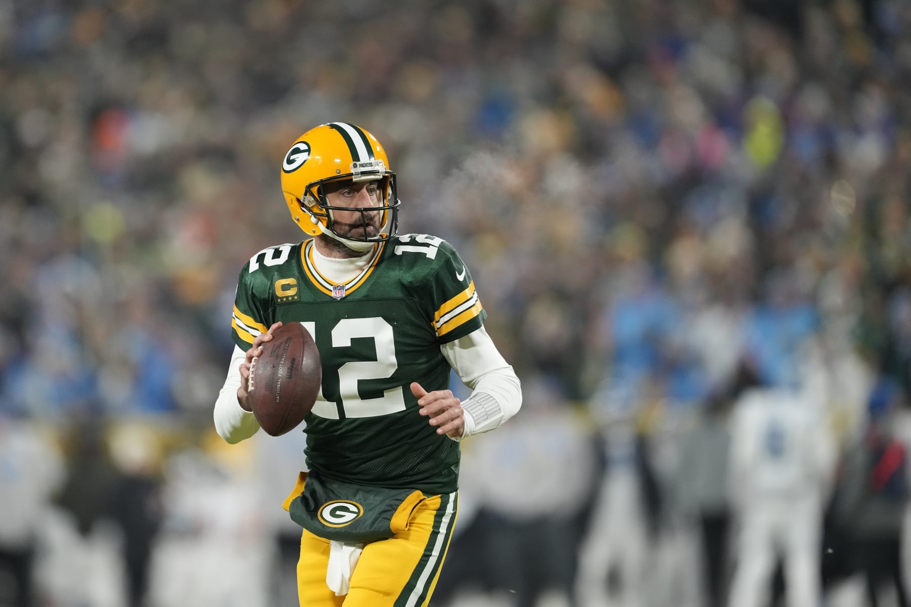 GREEN BAY, WISCONSIN - JANUARY 08: Aaron Rodgers #12 of the Green Bay Packers scrambles with the ball against the Detroit Lions in the first half at Lambeau Field on January 08, 2023 in Green Bay, Wisconsin. (Photo by Patrick McDermott/Getty Images)