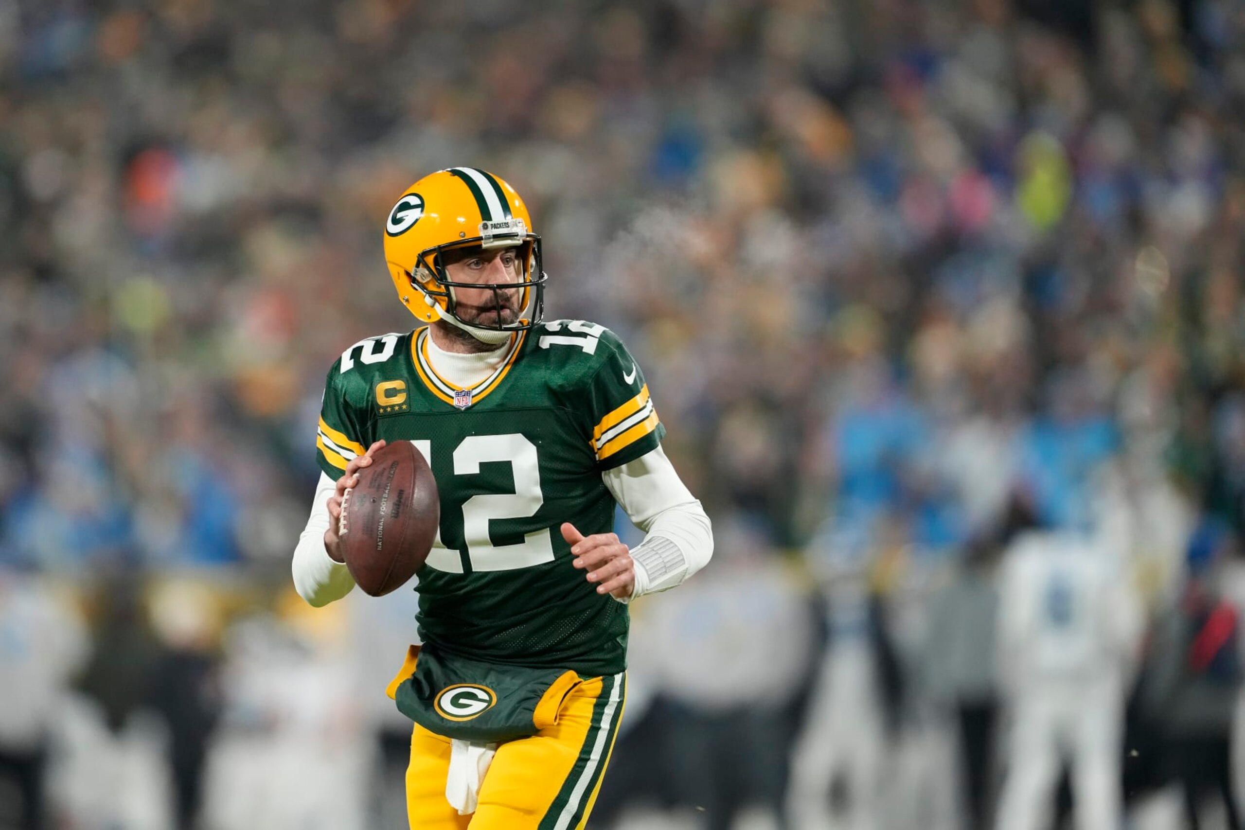 GREEN BAY, WISCONSIN - JANUARY 08: Aaron Rodgers #12 of the Green Bay Packers scrambles with the ball against the Detroit Lions in the first half at Lambeau Field on January 08, 2023 in Green Bay, Wisconsin. (Photo by Patrick McDermott/Getty Images)