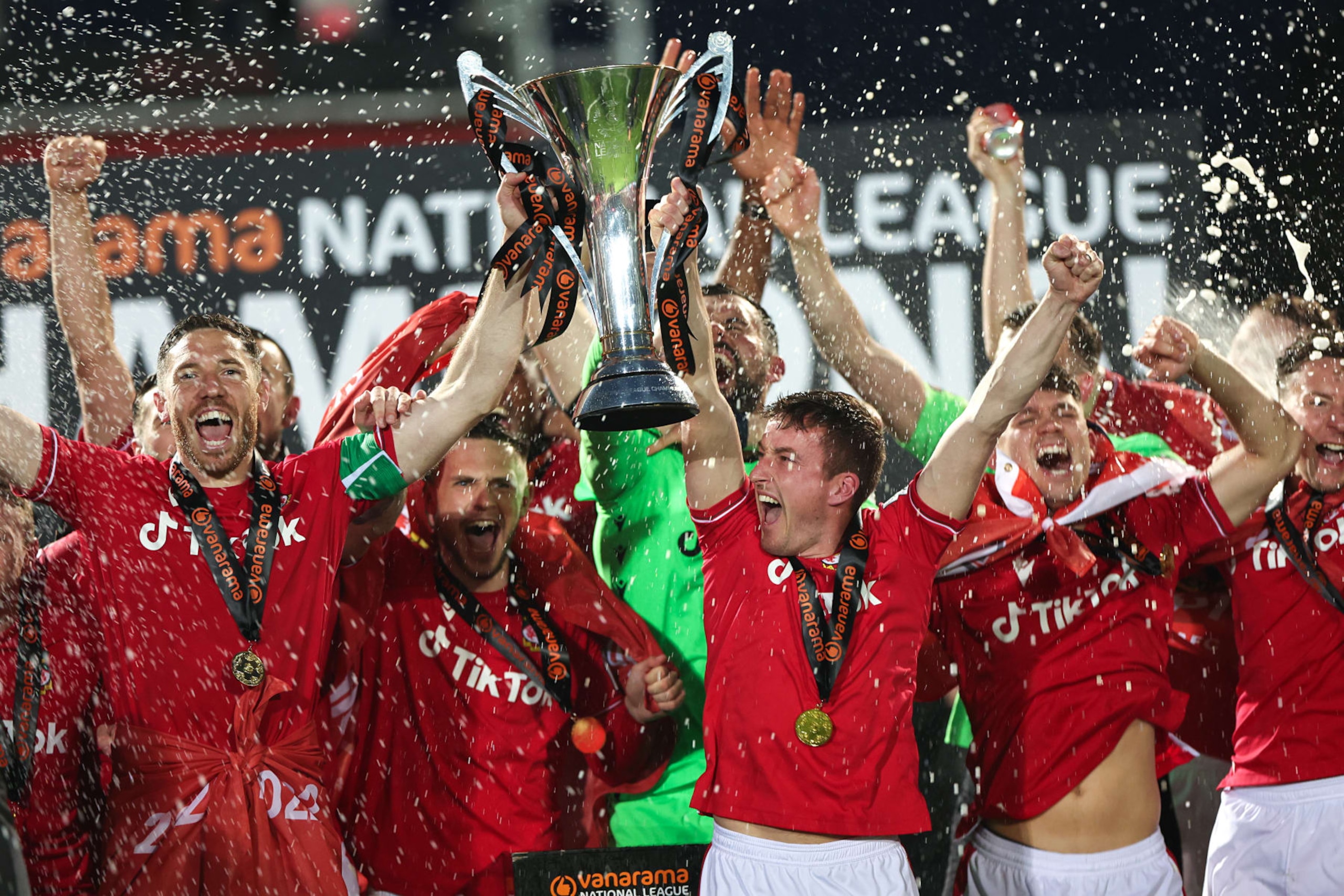 WREXHAM, WALES - APRIL 22: Ben Tozer and Luke Young of Wrexham lift the Vanarama National League Trophy as Wrexham celebrate promotion back to the English Football League during the Vanarama National League match between Wrexham and Boreham Wood at Racecourse Ground on April 22, 2023 in Wrexham, Wales. (Photo by Matthew Ashton - AMA/Getty Images)
