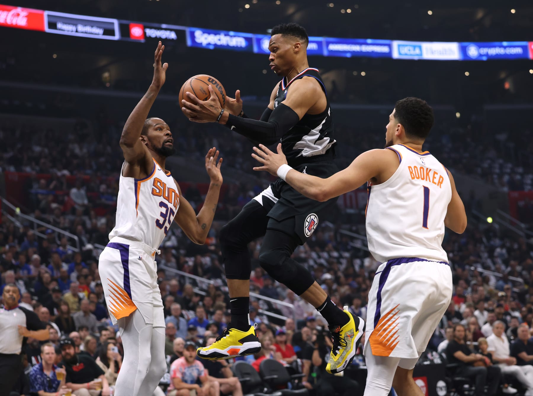 LOS ANGELES, CALIFORNIA - APRIL 22: Russell Westbrook #0 of the LA Clippers makes a pass as he cuts between Kevin Durant #35 and Devin Booker #1 of the Phoenix Suns during the first quarter of Game Four of the Western Conference First Round Playoffs at Crypto.com Arena on April 22, 2023 in Los Angeles, California. NOTE TO USER: User expressly acknowledges and agrees that, by downloading and or using this photograph, User is consenting to the terms and conditions of the Getty Images License Agreement. (Photo by Harry How/Getty Images)