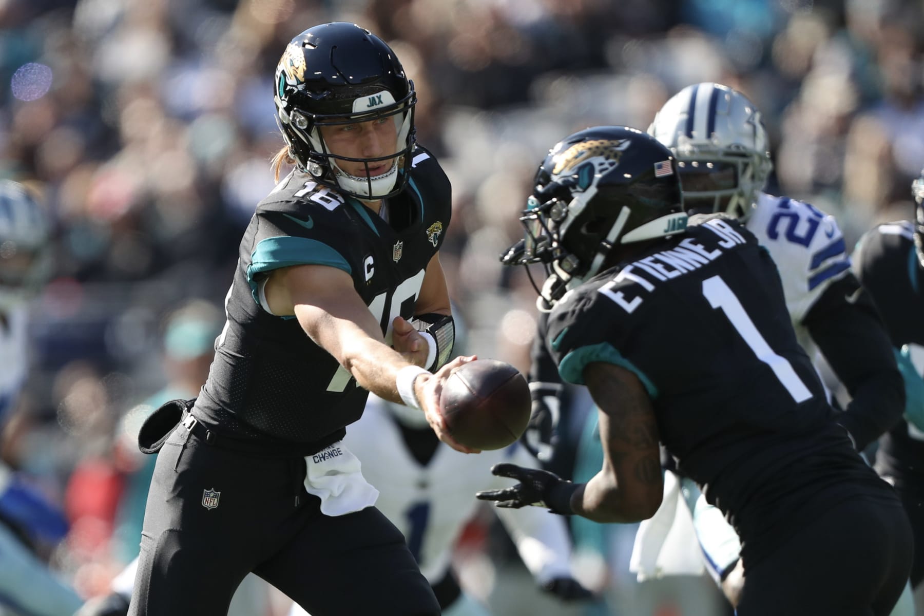 JACKSONVILLE, FLORIDA - DECEMBER 18: Trevor Lawrence #16 of the Jacksonville Jaguars hands off to Travis Etienne Jr. #1 during the first half against the Dallas Cowboys at TIAA Bank Field on December 18, 2022 in Jacksonville, Florida. (Photo by Courtney Culbreath/Getty Images)