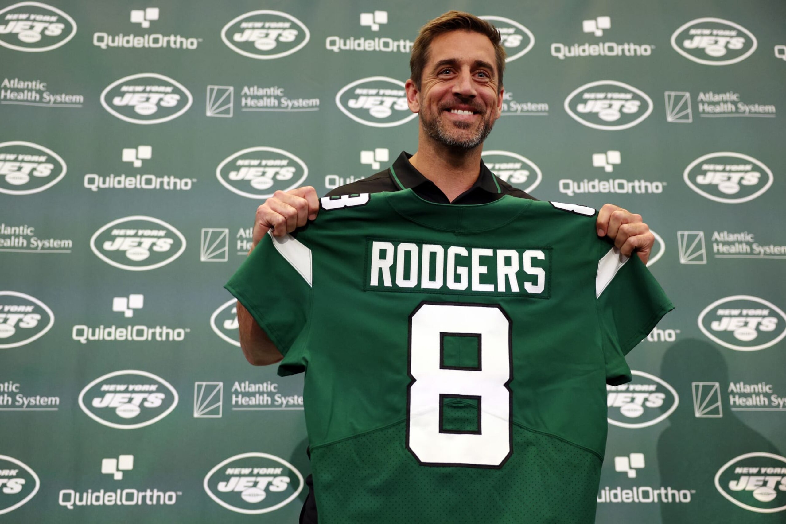FLORHAM PARK, NEW JERSEY - APRIL 26: New York Jets quarterback Aaron Rodgers poses with a jersey during an introductory press conference at Atlantic Health Jets Training Center on April 26, 2023 in Florham Park, New Jersey. (Photo by Elsa/Getty Images)