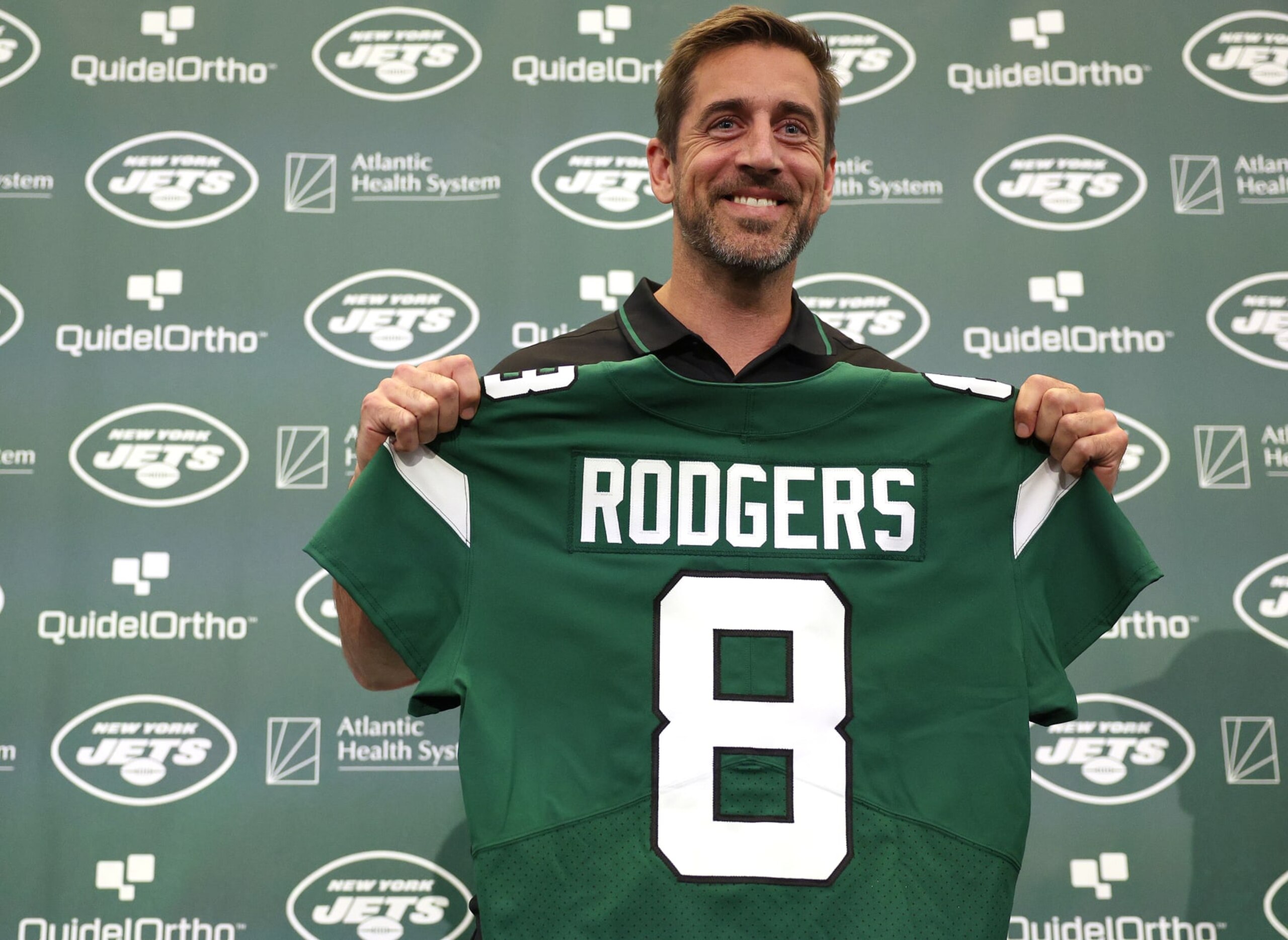 FLORHAM PARK, NEW JERSEY - APRIL 26: New York Jets quarterback Aaron Rodgers poses with a jersey during an introductory press conference at Atlantic Health Jets Training Center on April 26, 2023 in Florham Park, New Jersey. (Photo by Elsa/Getty Images)