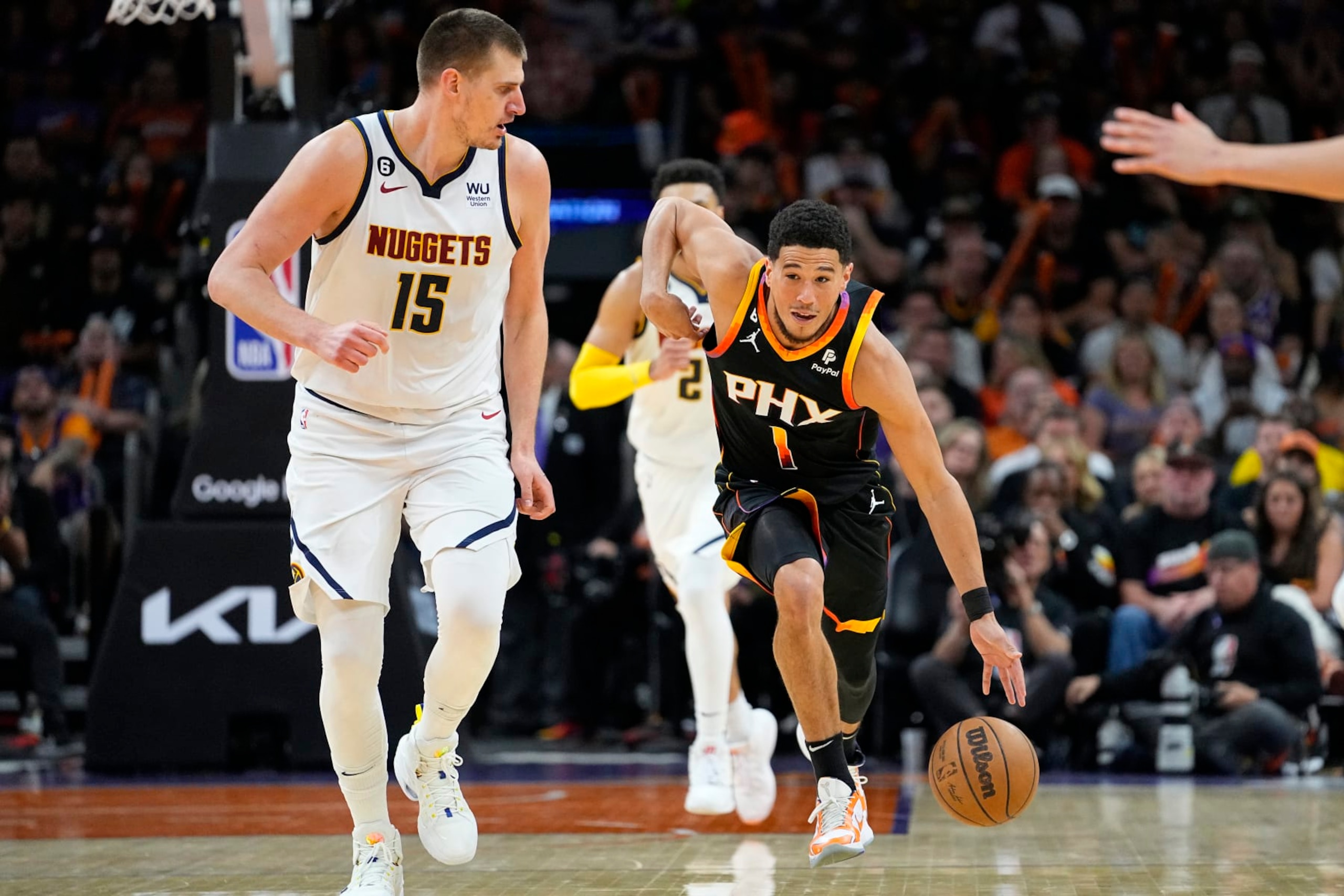 Phoenix Suns guard Devin Booker (1) drives as Denver Nuggets center Nikola Jokic (15) looks on during the first half of Game 4 of an NBA basketball Western Conference semifinal game, Sunday, May 7, 2023, in Phoenix. (AP Photo/Matt York) Phoenix Suns guard Devin Booker (1) drives as Denver Nuggets center Nikola Jokic (15) looks on during the first half of Game 4 of an NBA basketball Western Conference semifinal game, Sunday, May 7, 2023, in Phoenix. (AP Photo/Matt York)