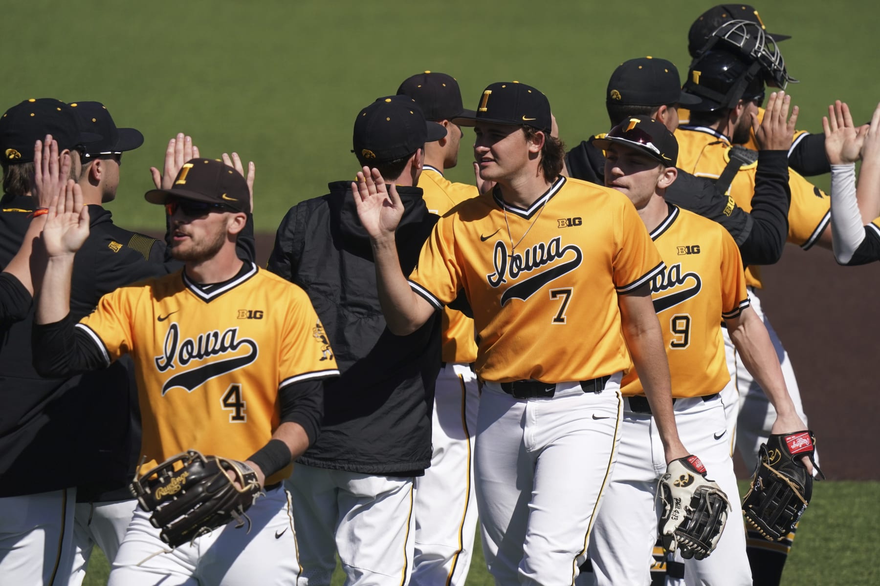 Iowa's Keaton Anthony (7), Brayden Frazier (4), and Kyle Huckstorf (9) high five teammates after an NCAA baseball game against Bucknell on Sunday, Feb. 20, 2022, in Charleston, S.C. Iowa won 3-0. (AP Photo/Sean Rayford)