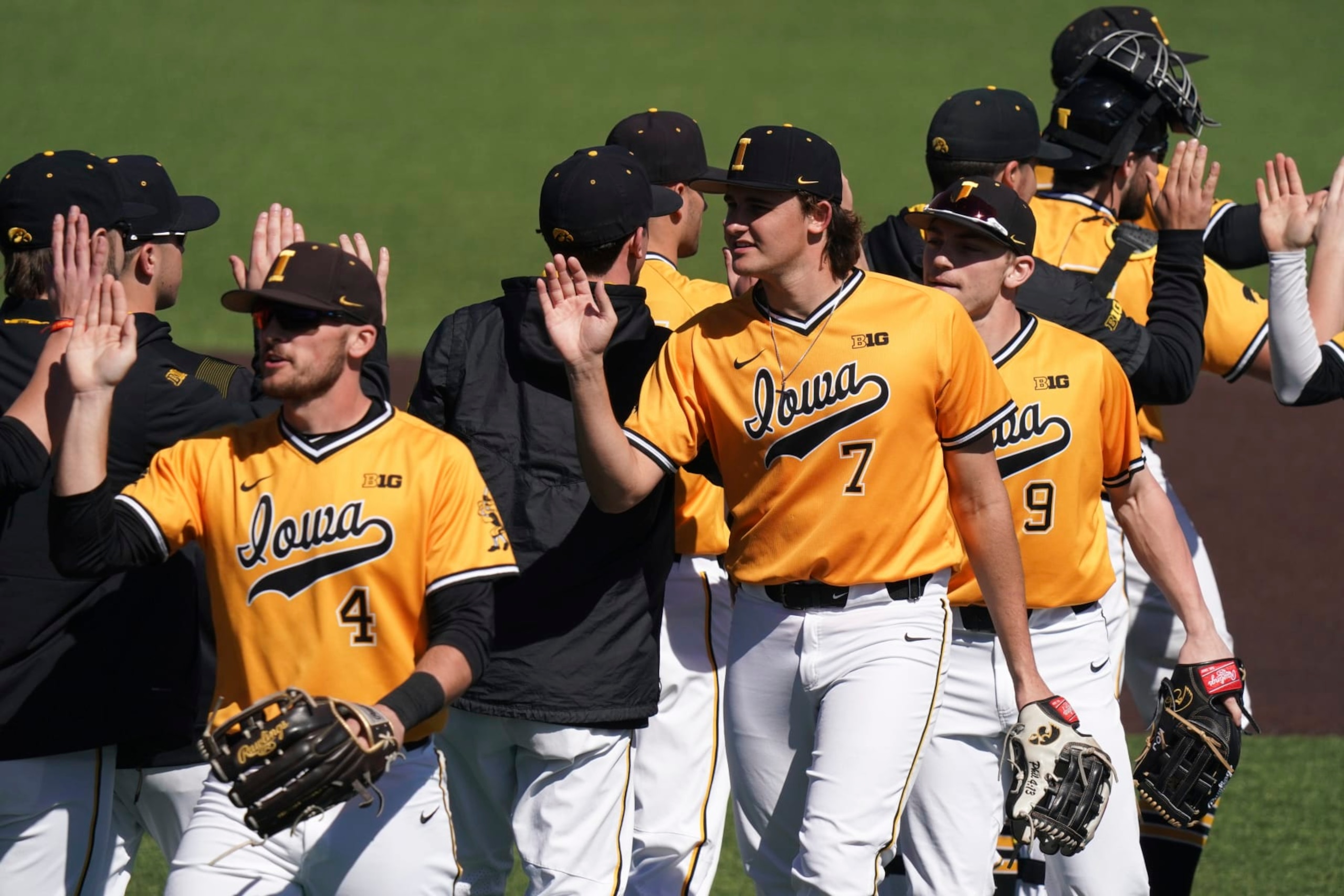 Iowa's Keaton Anthony (7), Brayden Frazier (4), and Kyle Huckstorf (9) high five teammates after an NCAA baseball game against Bucknell on Sunday, Feb. 20, 2022, in Charleston, S.C. Iowa won 3-0. (AP Photo/Sean Rayford)