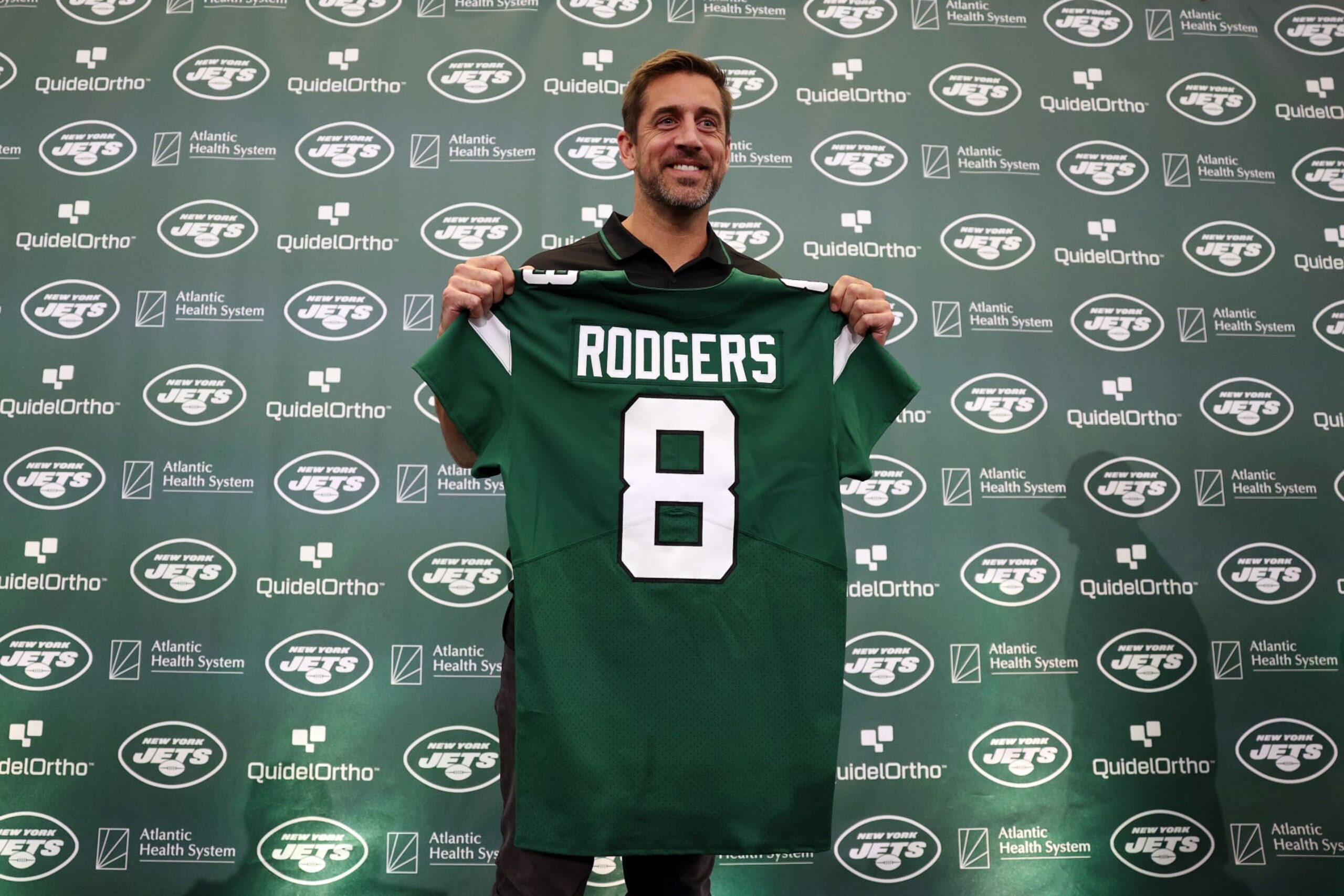 FLORHAM PARK, NEW JERSEY - APRIL 26: New York Jets quarterback Aaron Rodgers poses with a jersey during an introductory press conference at Atlantic Health Jets Training Center on April 26, 2023 in Florham Park, New Jersey. (Photo by Elsa/Getty Images)