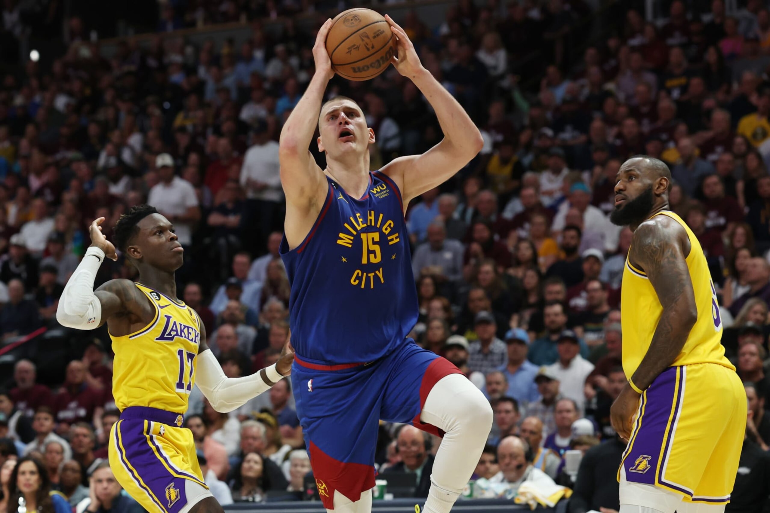 DENVER, COLORADO - MAY 16: Nikola Jokic #15 of the Denver Nuggets shoots the ball between Dennis Schroder #17 and LeBron James #6 of the Los Angeles Lakers during the third quarter in game one of the Western Conference Finals at Ball Arena on May 16, 2023 in Denver, Colorado. NOTE TO USER: User expressly acknowledges and agrees that, by downloading and or using this photograph, User is consenting to the terms and conditions of the Getty Images License Agreement. (Photo by Matthew Stockman/Getty Images)