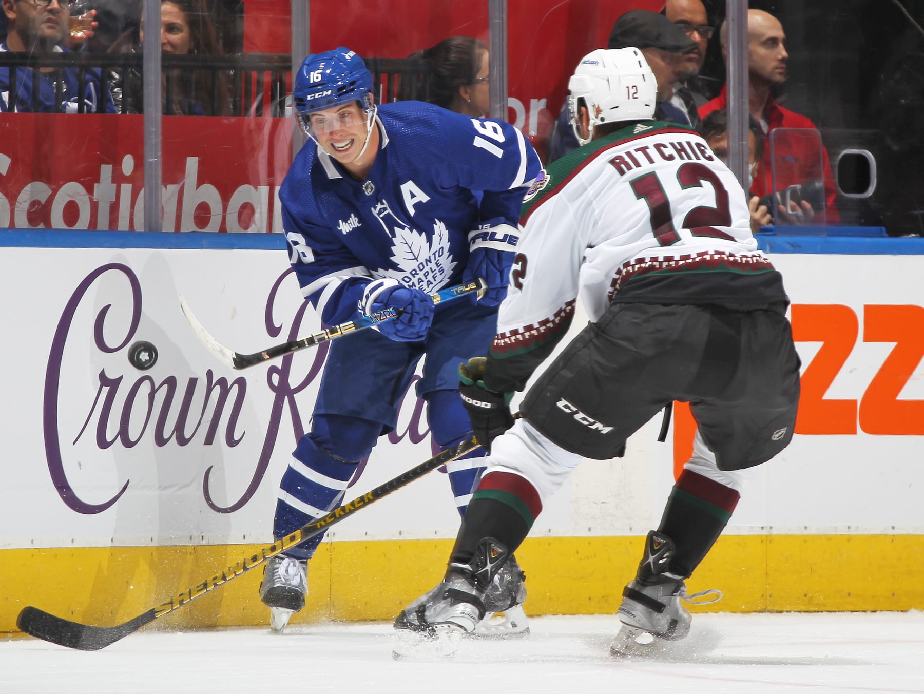 TORONTO, CANADA - OCTOBER 17:  Mitchell Marner #16 of the Toronto Maple Leafs flips the puck past Nick Ritchie #12 of the Arizona Coyotes during an NHL game at Scotiabank Arena on October 17, 2022 in Toronto, Ontario, Canada. (Photo by Claus Andersen/Getty Images)