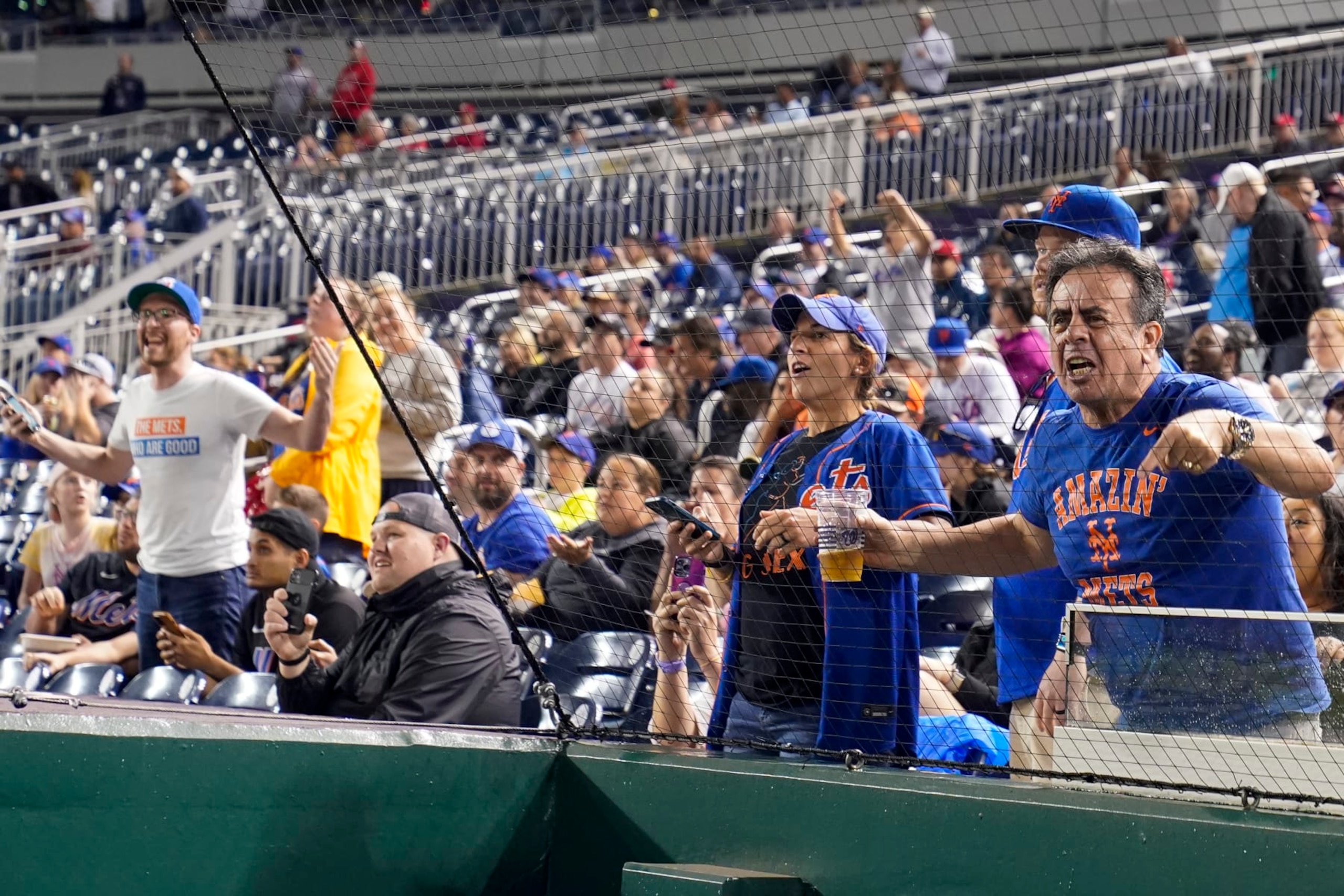 New York Mets fans react after it was announced, after a nearly four-hour weather delay, that the day's baseball game would resume Sunday as part of a doubleheader against the Washington Nationals at Nationals Park, Saturday, May 13, 2023, in Washington. (AP Photo/Alex Brandon)