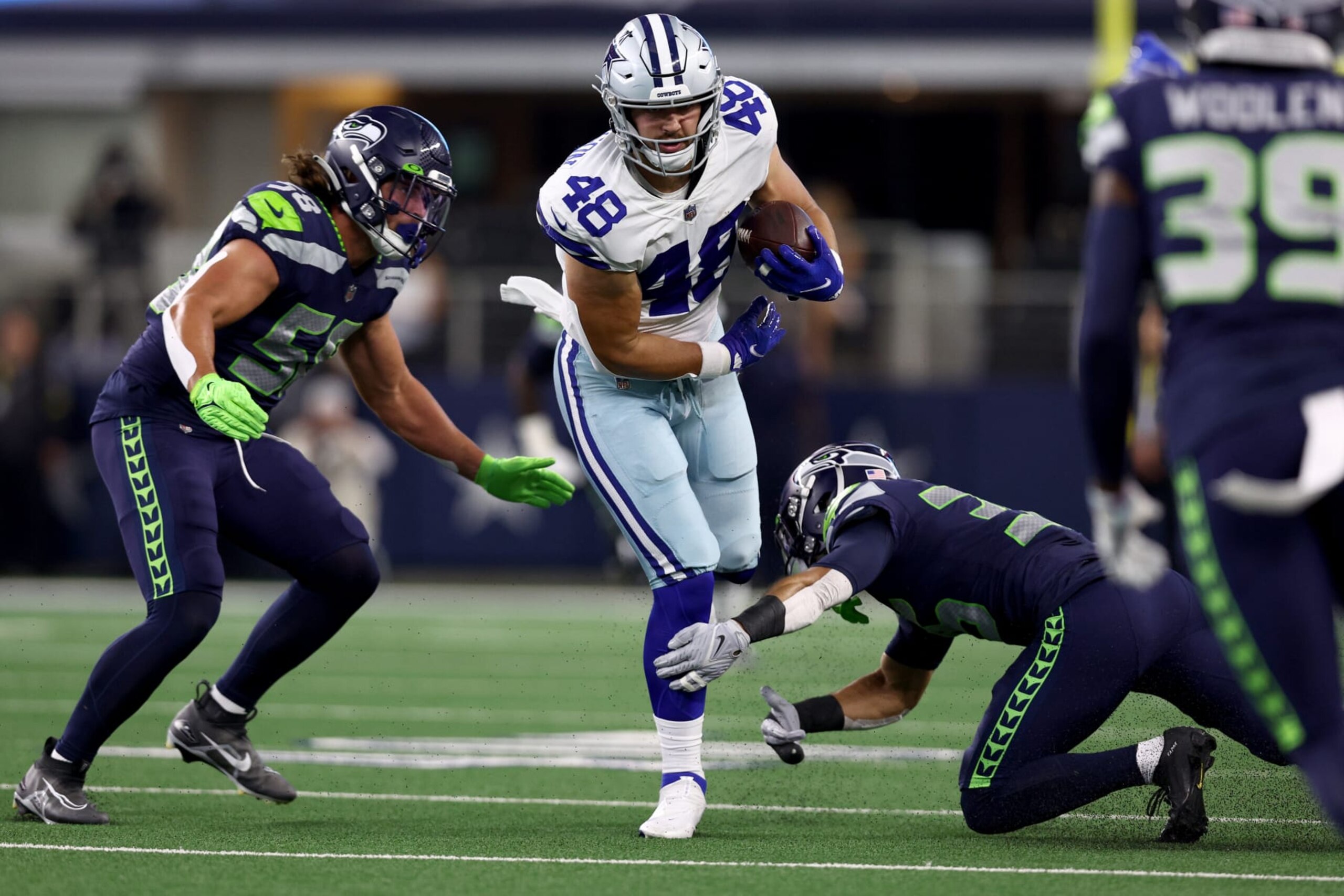 ARLINGTON, TEXAS - AUGUST 26: Tight end Jake Ferguson #48 of the Dallas Cowboys carries the ball against linebacker Tanner Muse #58 of the Seattle Seahawks in the first half of a NFL preseason football game at AT&T Stadium on August 26, 2022 in Arlington, Texas. (Photo by Tom Pennington/Getty Images)