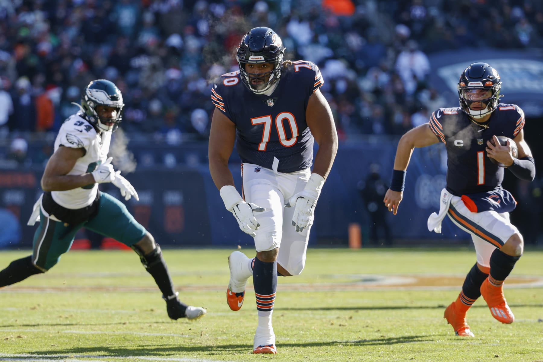 Chicago Bears offensive tackle Braxton Jones (70) blocks as quarterback Justin Fields (1) rushes with the ball during the first half of an NFL football game against the Philadelphia Eagles, Sunday, Dec. 18, 2022, in Chicago. (AP Photo/Kamil Krzaczynski)