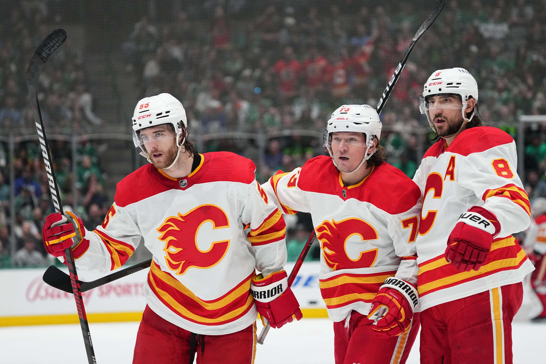 DALLAS, TX - MARCH 6: Noah Hanifin #55, Tyler Toffoli #73 and Chris Tanev #8 of the Calgary Flames celebrate a goal against the Dallas Stars at the American Airlines Center on March 6, 2023 in Dallas, Texas. (Photo by Glenn James/NHLI via Getty Images)
