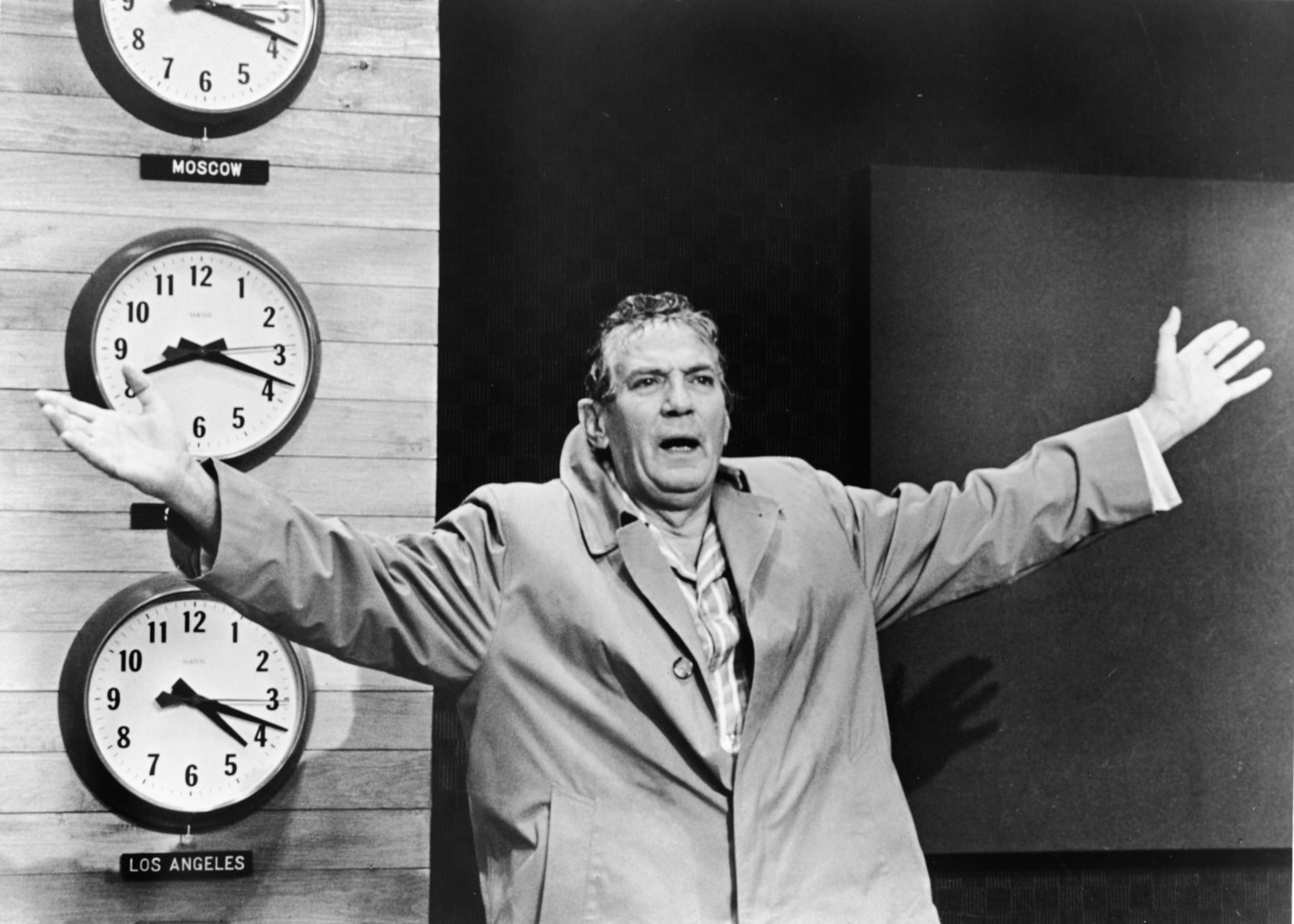 British-born actor Peter Finch wears a raincoat and raises his arms in a still from the film, 'Network', directed by Sydney Lumet, 1976. (Photo by MGM Studios/Courtesy of Getty Images)