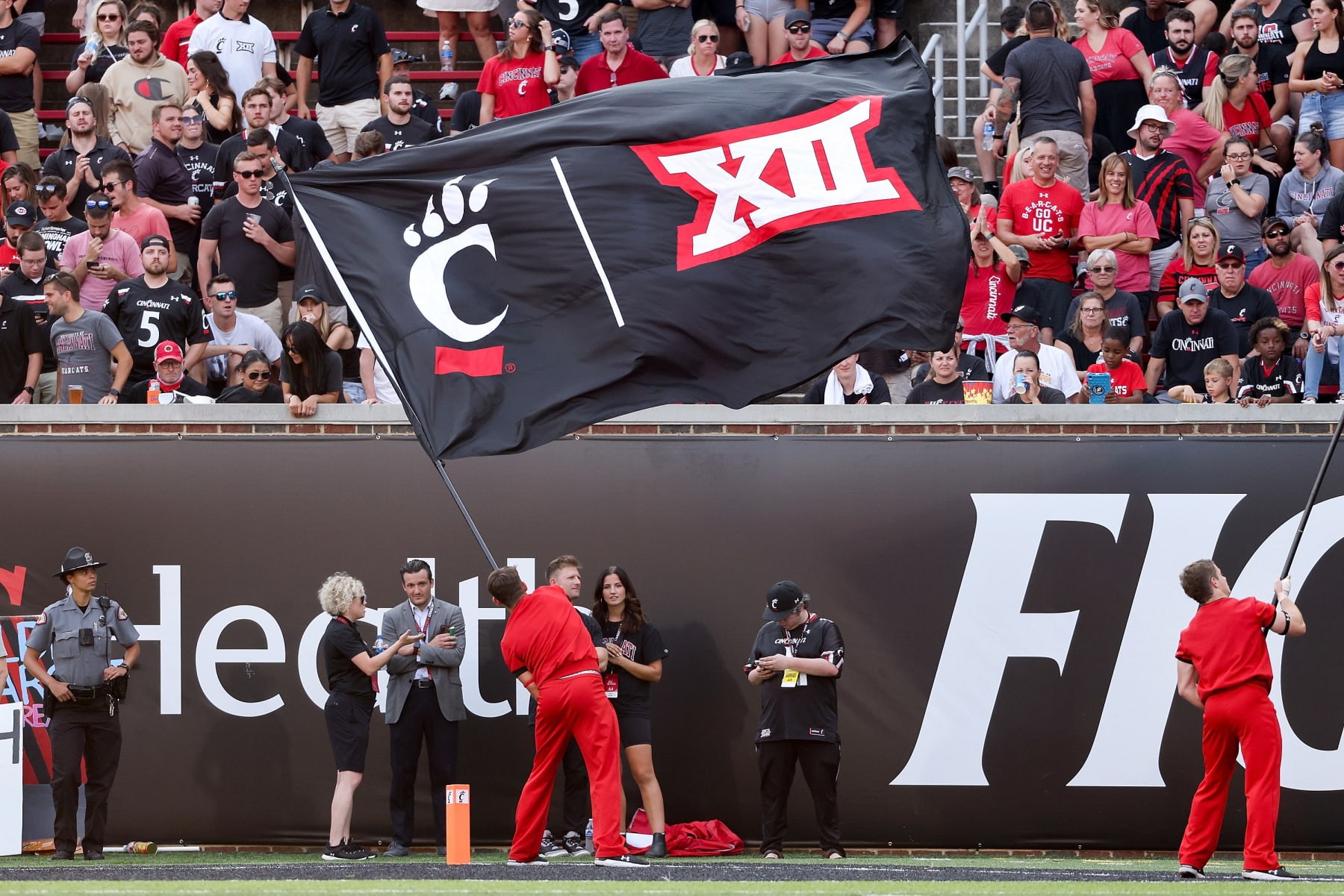 CINCINNATI, OHIO - SEPTEMBER 11: A Cincinnati Bearcats cheerleader waves a flag with the Cincinnati Bearcats and Big 12 logos during the game against the Murray State Racers at Nippert Stadium on September 11, 2021 in Cincinnati, Ohio. (Photo by Dylan Buell/Getty Images)